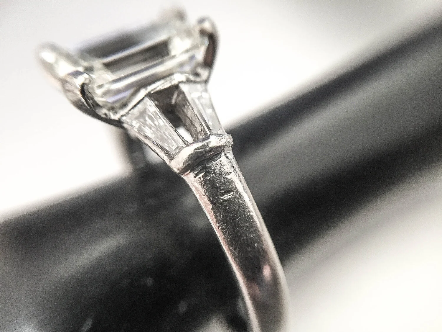  Image 1. Evidence of hard impact marks on the shoulder and setting edges that hold the tapered baguette diamonds. As the setting edge is still visible and complete, it is likely that the centre baguette broke in two and was then able to fall out. 