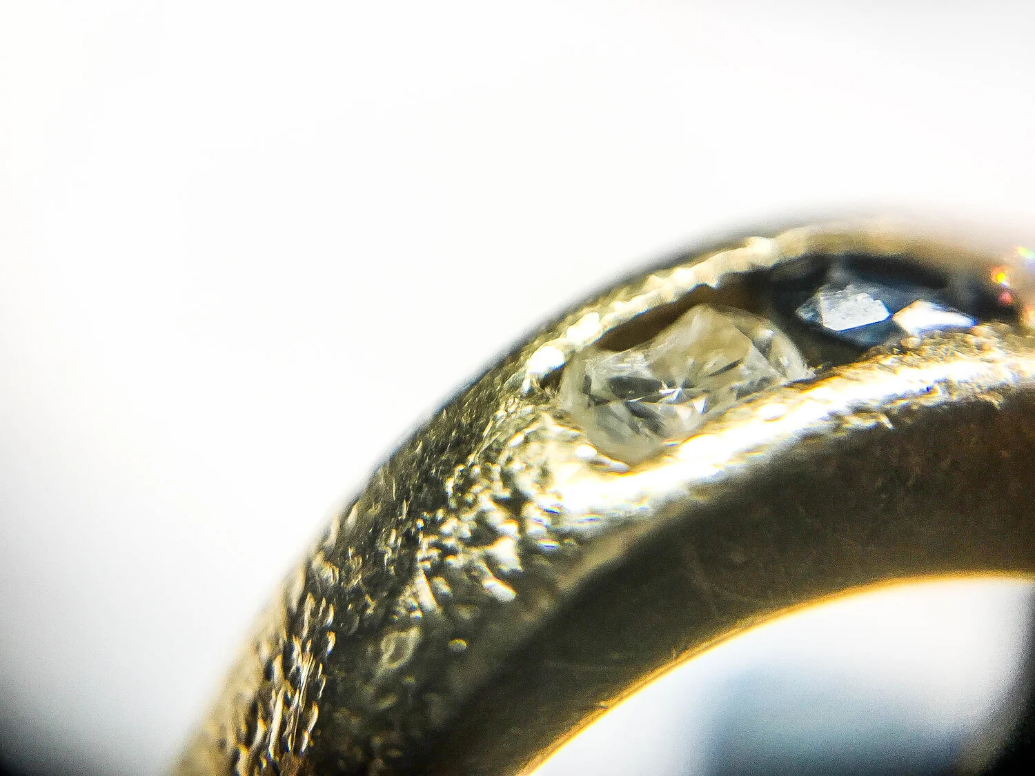  Image 3. Here we can see smooth, small, rounded impact marks covering most of the surface, worn sapphire edges and a broken diamond, all caused by banging against a claw set ring. 
