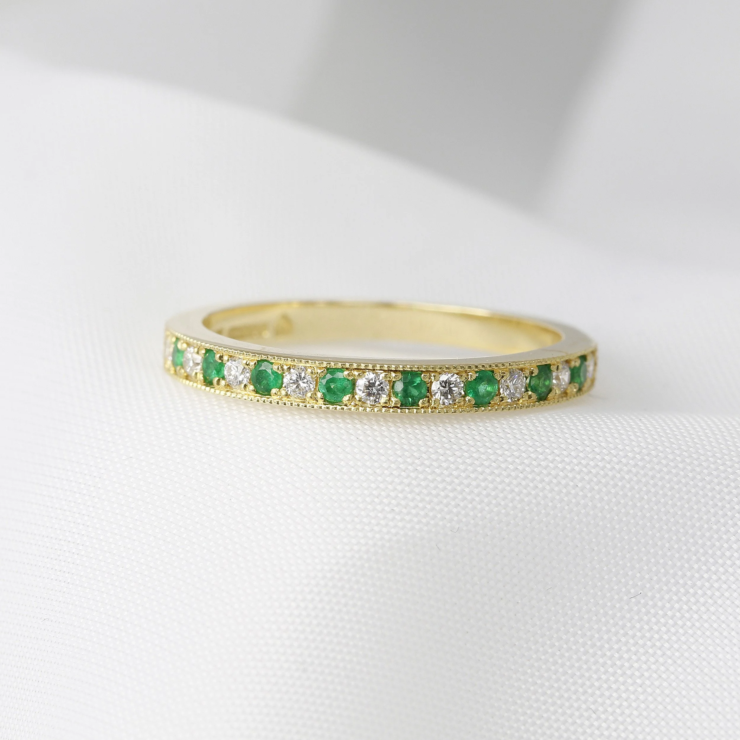  Emerald & Diamond Half Eternity Ring in Yellow Gold £850.00. Our Chichester Cross mark can be seen in the back left of the ring. 