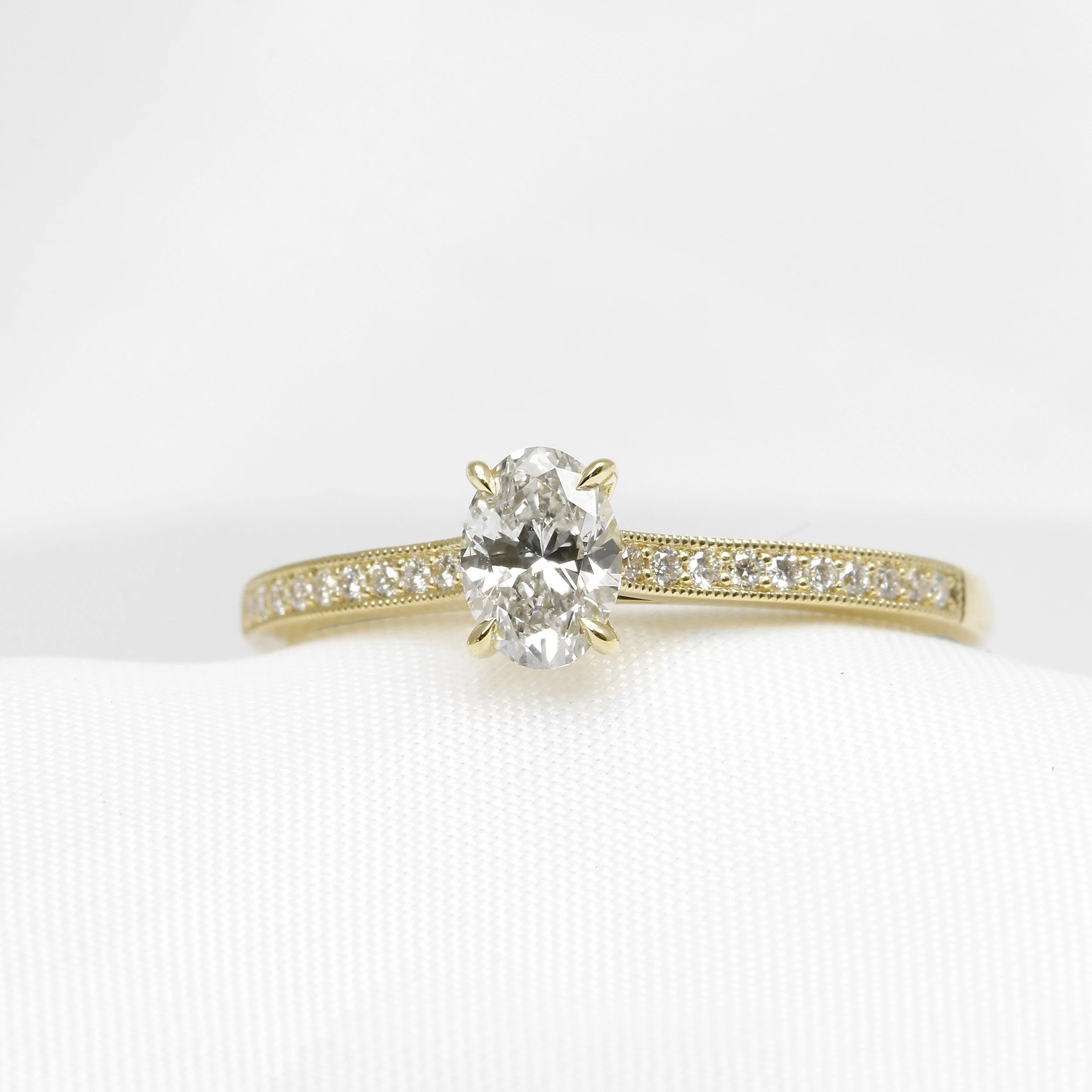  Oval diamond solitaire ring in yellow gold with diamond shoulders  