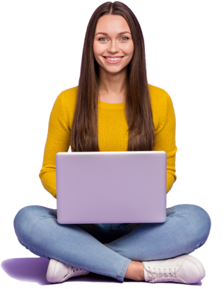 A young woman sitting cross-legged on the floor, smiling, holding a laptop, wearing a yellow sweater and blue jeans.