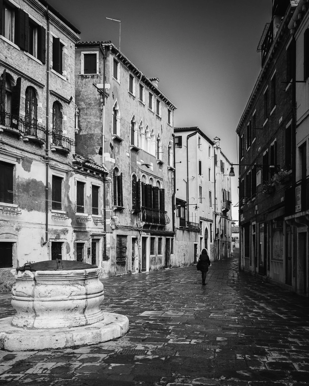 Schmale, verlassene Straßen in einer alten europäischen Stadt, im Schwarz-Weiß-Stil, mit einer einsamen Person, die läuft.
