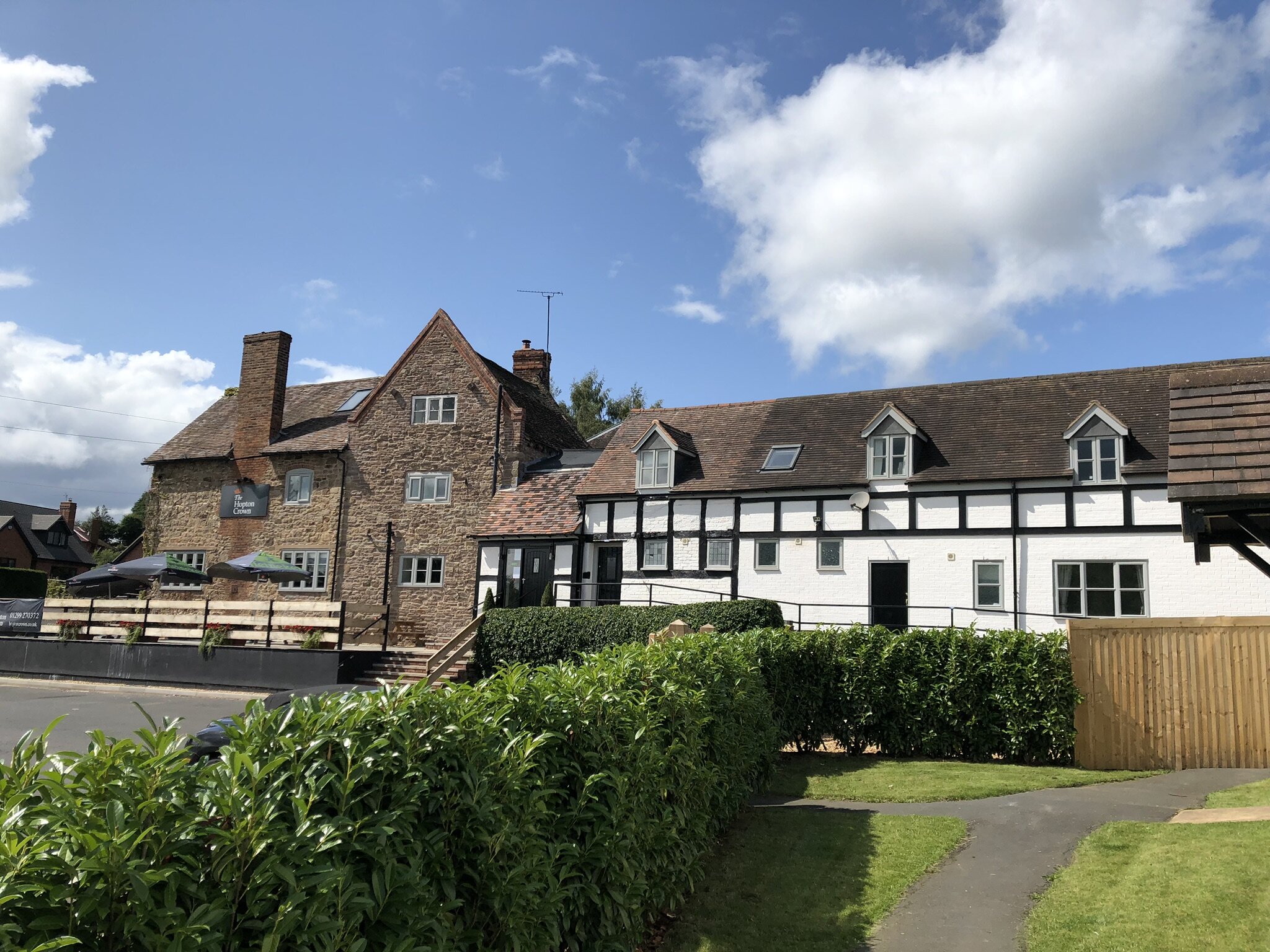 Historic stone and white half-timbered building with gabled roof and lush greenery.