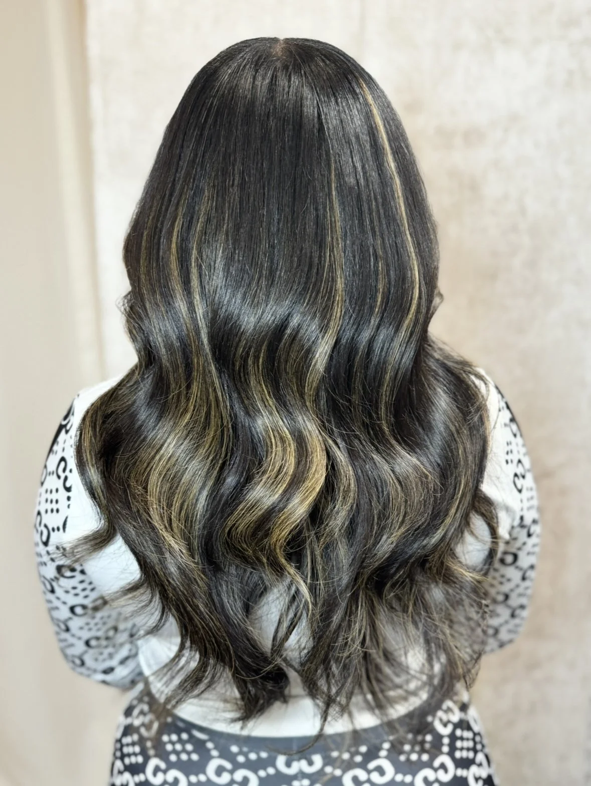 Back of a woman with wavy, dark hair with blonde highlights.