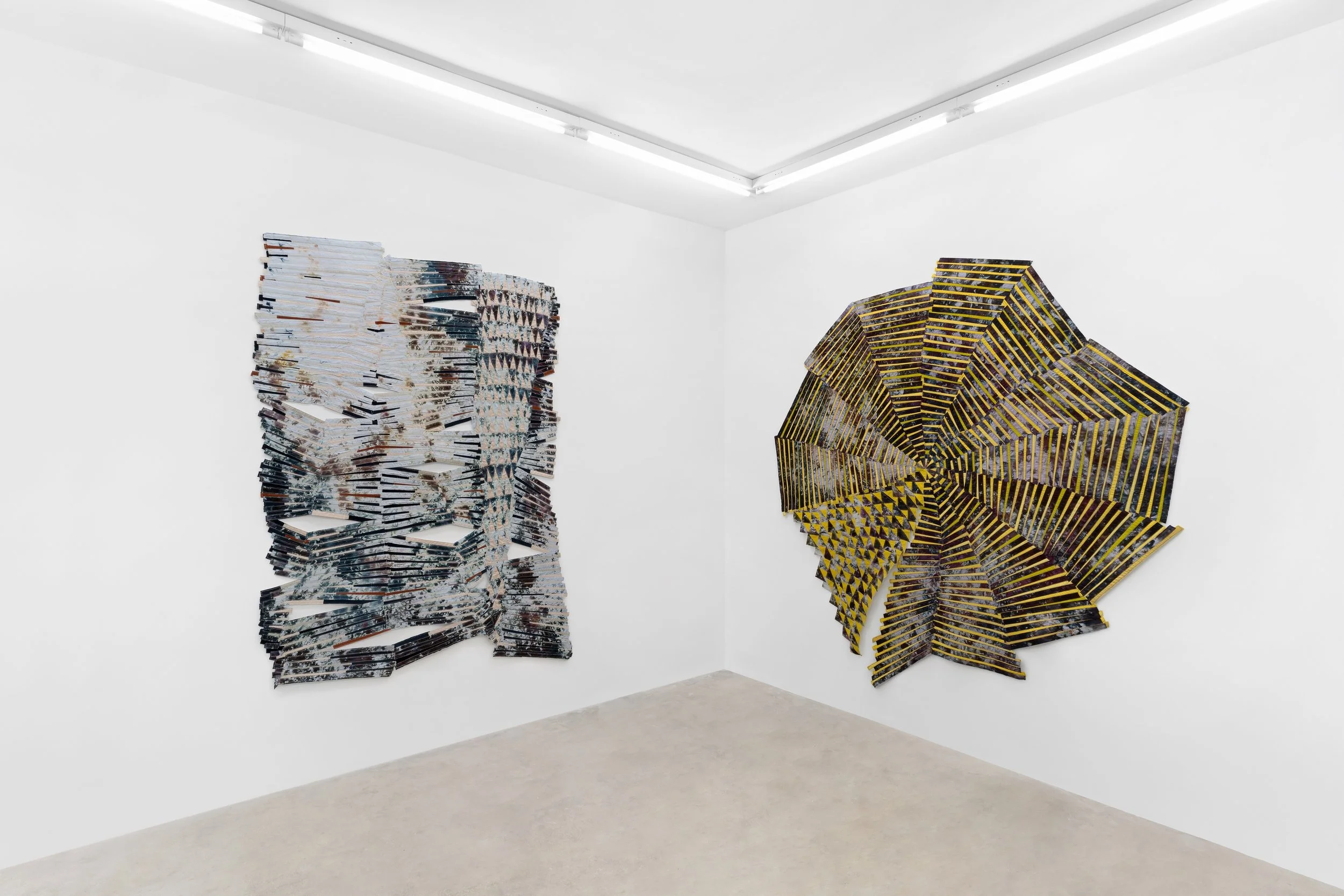 Baker–Hall Gallery - Regina Durante Jestrow: 'Everything Mixing Always' installation view of geometric abstract art quilts made from hand-dyed and found textiles arranged in geometric stripes and triangle patterns in an art gallery with white walls.