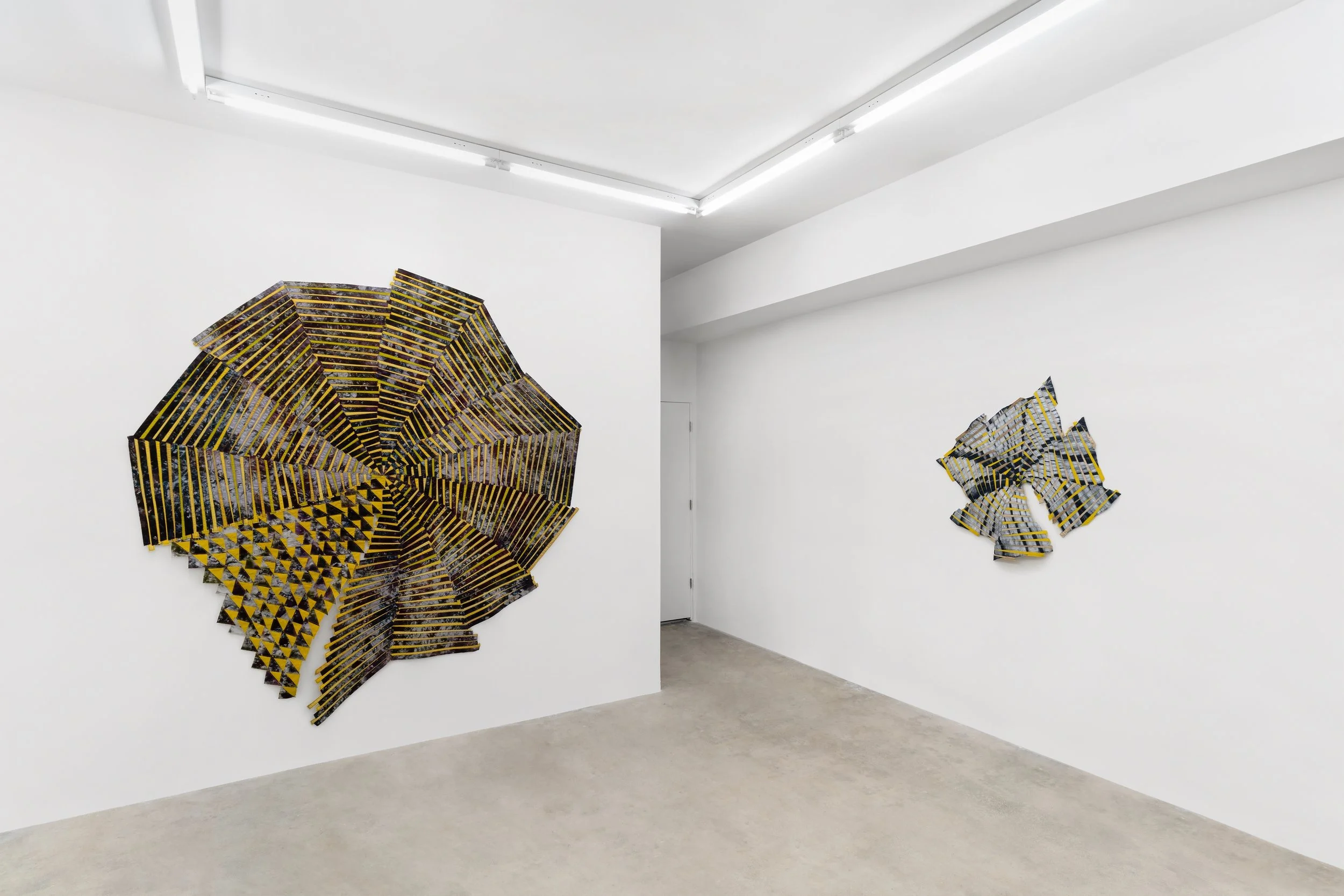 Baker–Hall Gallery - Regina Durante Jestrow: 'Everything Mixing Always' installation view of geometric abstract art quilts made from hand-dyed and found textiles arranged in geometric stripes and triangle patterns in an art gallery with white walls.