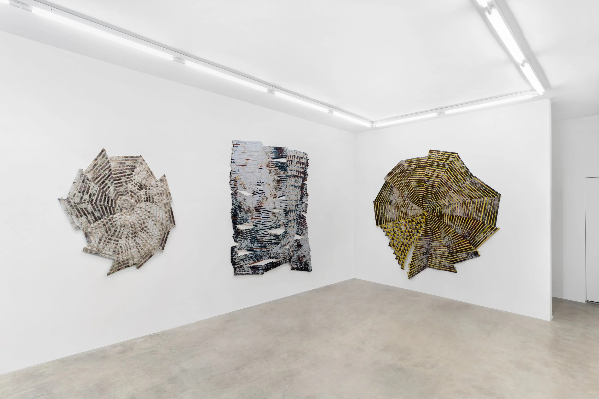 Baker–Hall Gallery - Regina Durante Jestrow: 'Everything Mixing Always' installation view of geometric abstract art quilts made from hand-dyed and found textiles arranged in geometric stripes and triangle patterns in an art gallery with white walls.