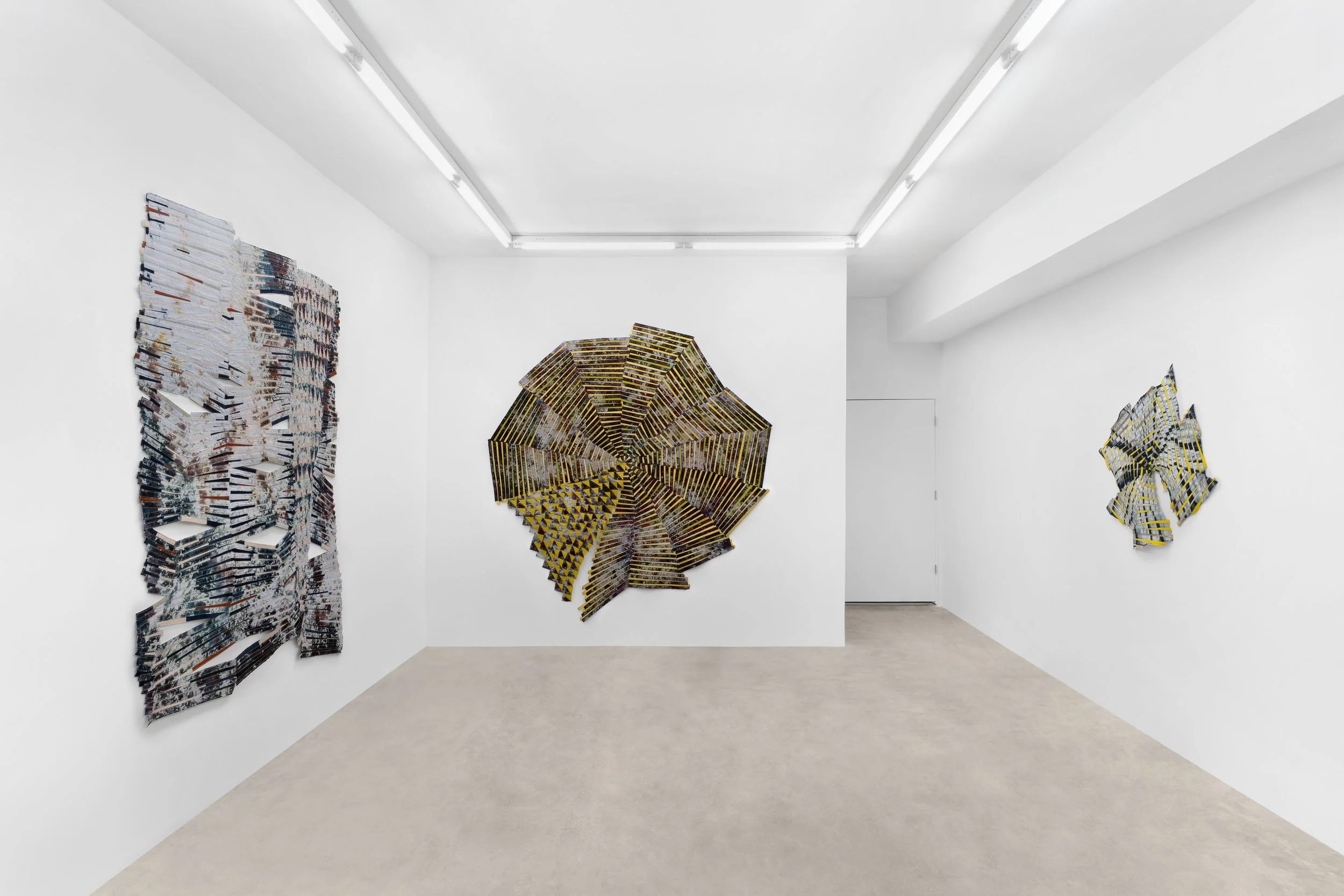 Baker–Hall Gallery - Regina Durante Jestrow: 'Everything Mixing Always' installation view of geometric abstract art quilts made from hand-dyed and found textiles arranged in geometric stripes and triangle patterns in an art gallery with white walls.