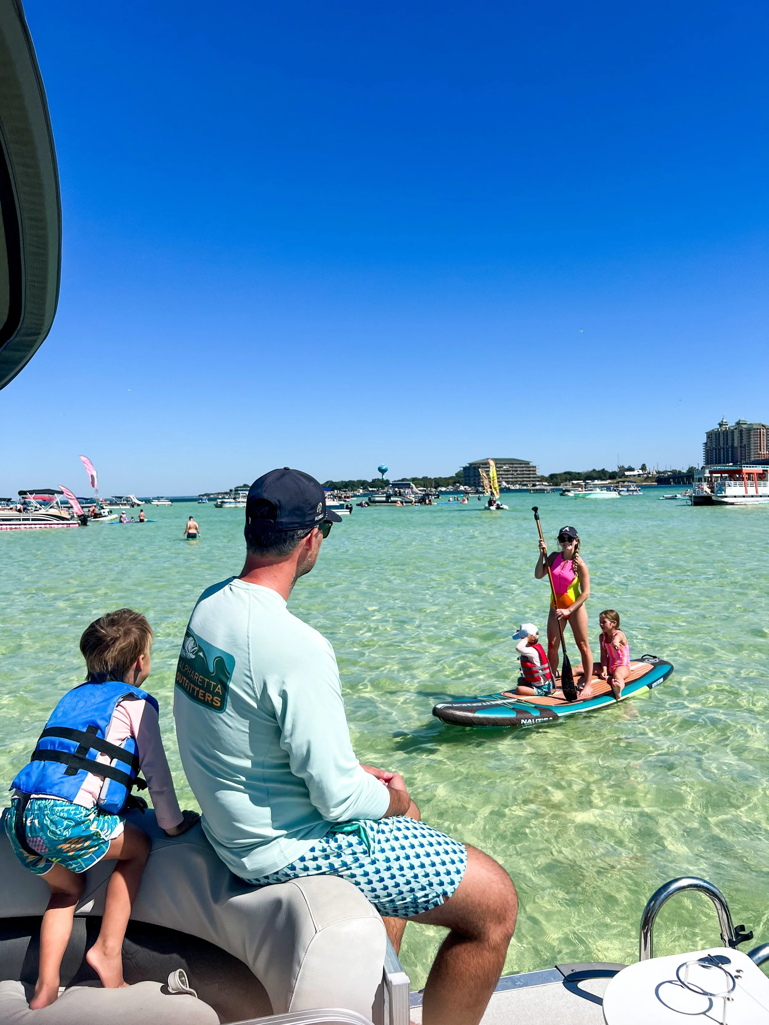 Father and son watching Mom and sisters paddleboarding on Crab Island.