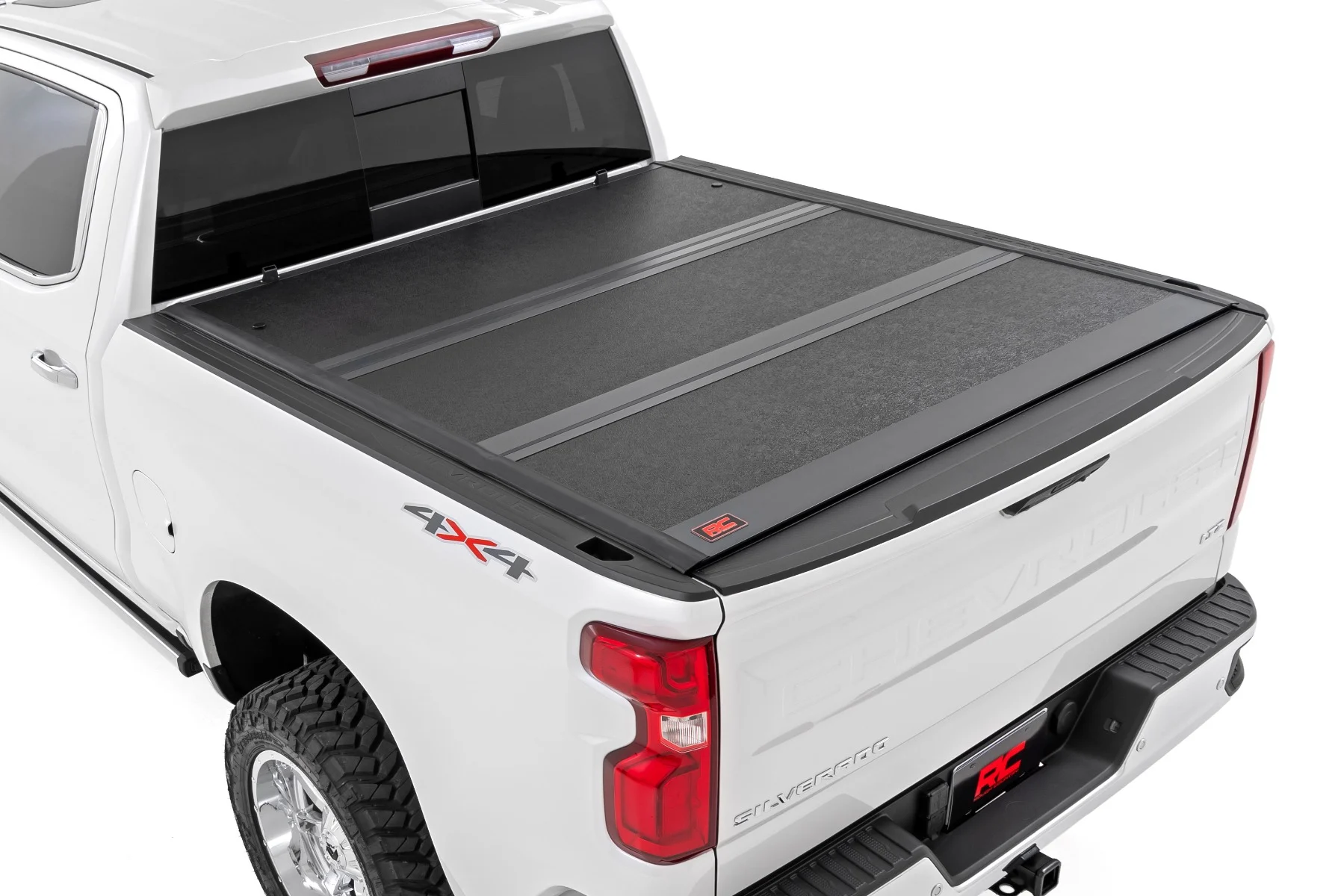 Rear view of a white Chevrolet Silverado pickup truck with a closed tonneau cover over the truck bed.
