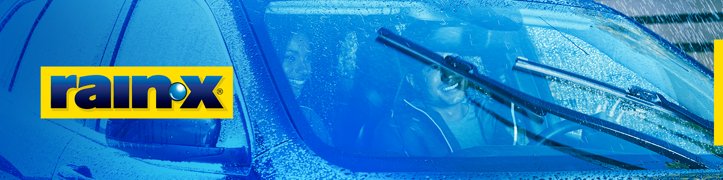A car with rain droplets on it and two smiling people inside. The Rain-X logo is displayed on the left.