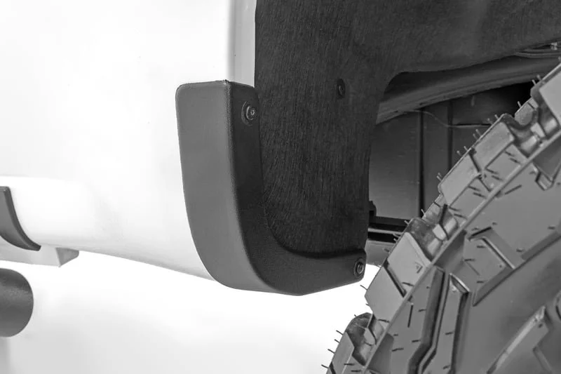 Close-up of a modular plastic bumper on the rear of a vehicle, showing the attachment points and part of the tire.