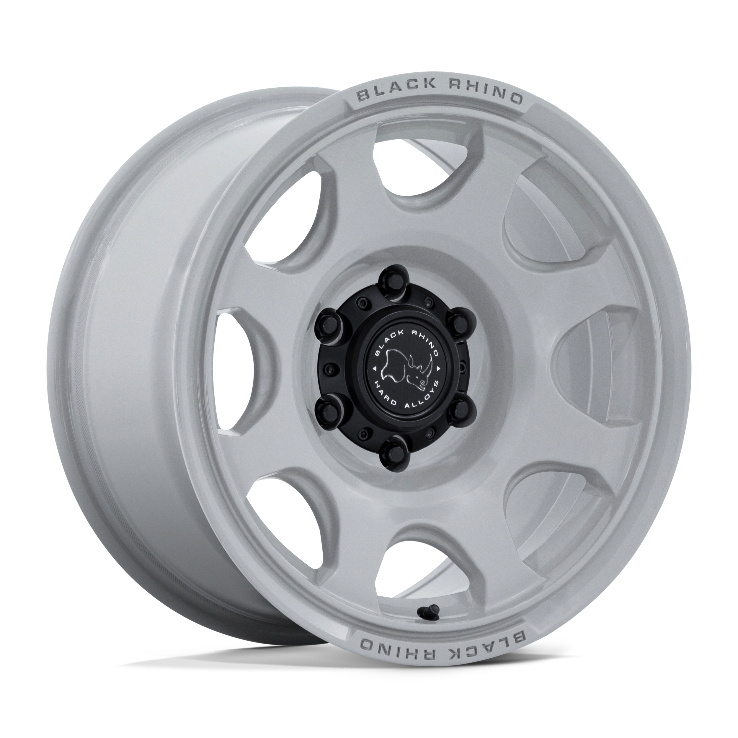 White wheel rim with black center cap and lug nuts, labeled "Black Rhino Hard Alloys," featuring oval cutouts and a small black valve stem.