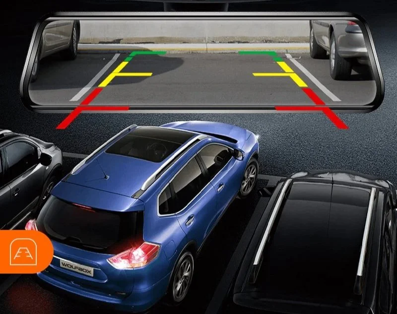 Rearview mirror showing parking lot with marked parking space, surrounded by parked cars, including a blue hatchback, with guide lines in green, yellow, and red for parking assistance.