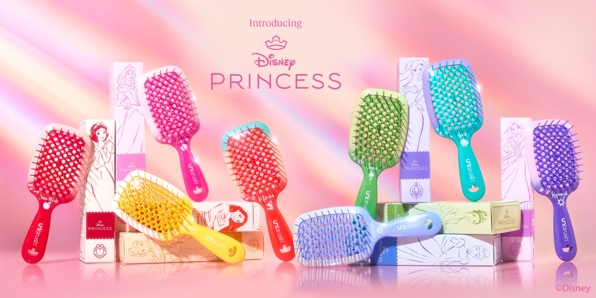 Colorful hairbrushes featuring Disney Princess designs. The brushes are arranged on a pink background with boxes behind them, showcasing princess characters and rainbow colors.