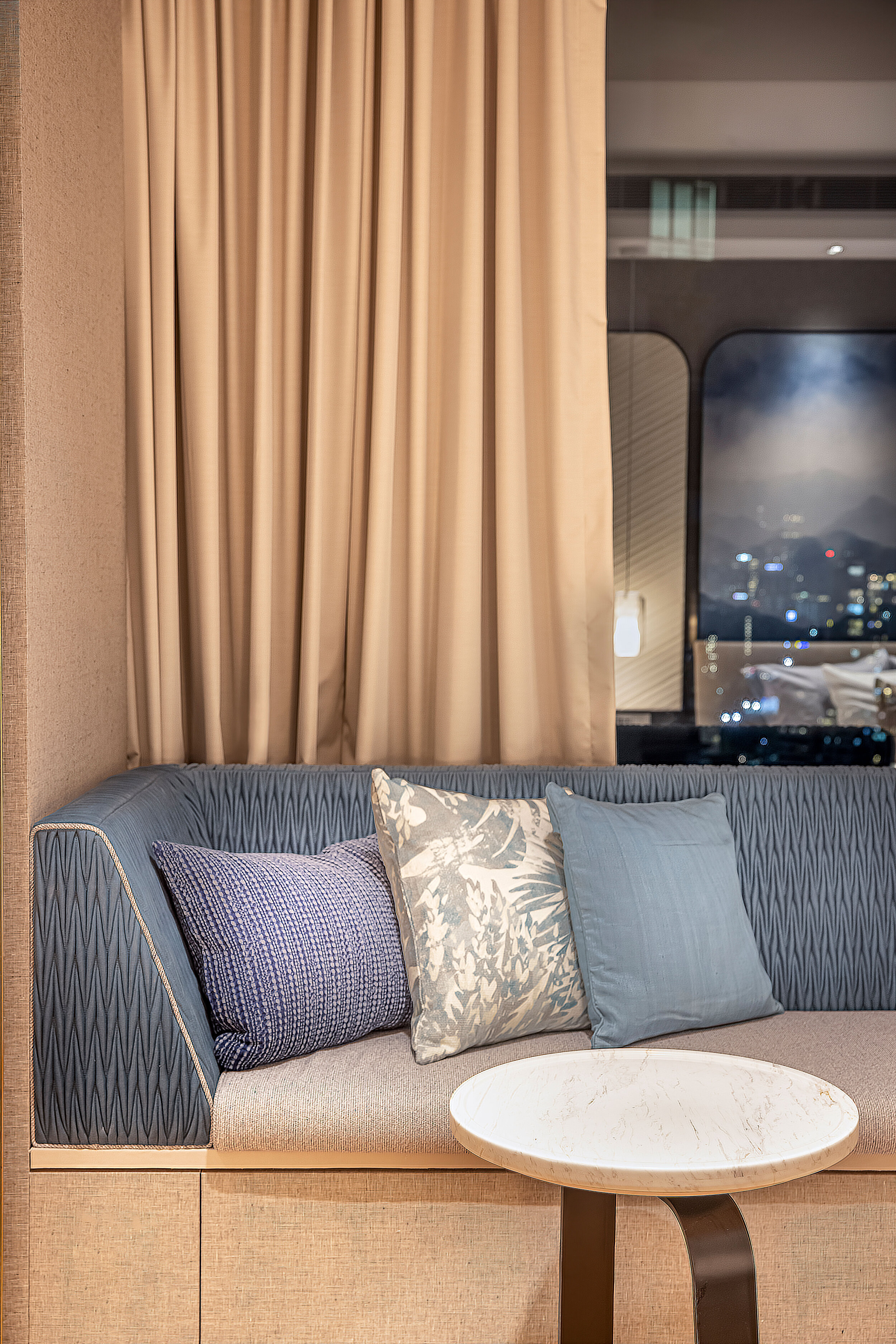 cropped image of a seat with blue fabric backing, blue and white cushions and round side table