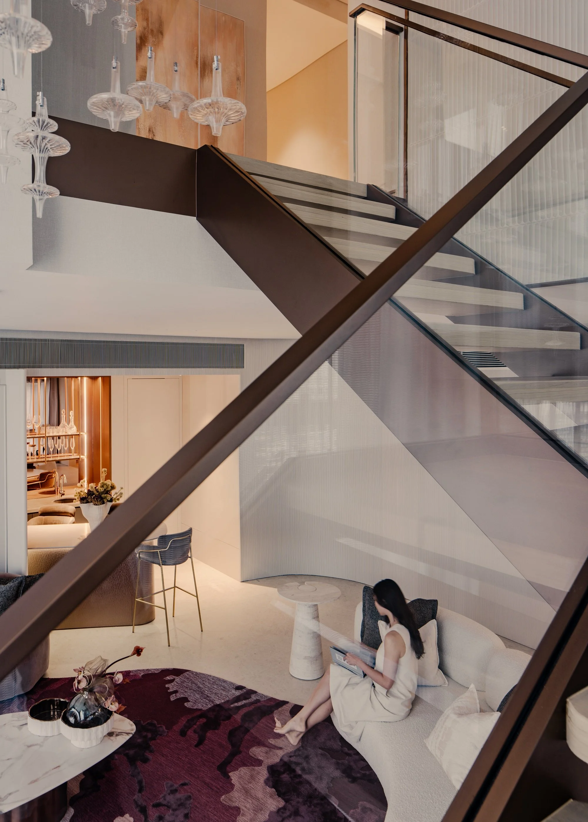 Looking at the living room from the staircase, a woman is reading