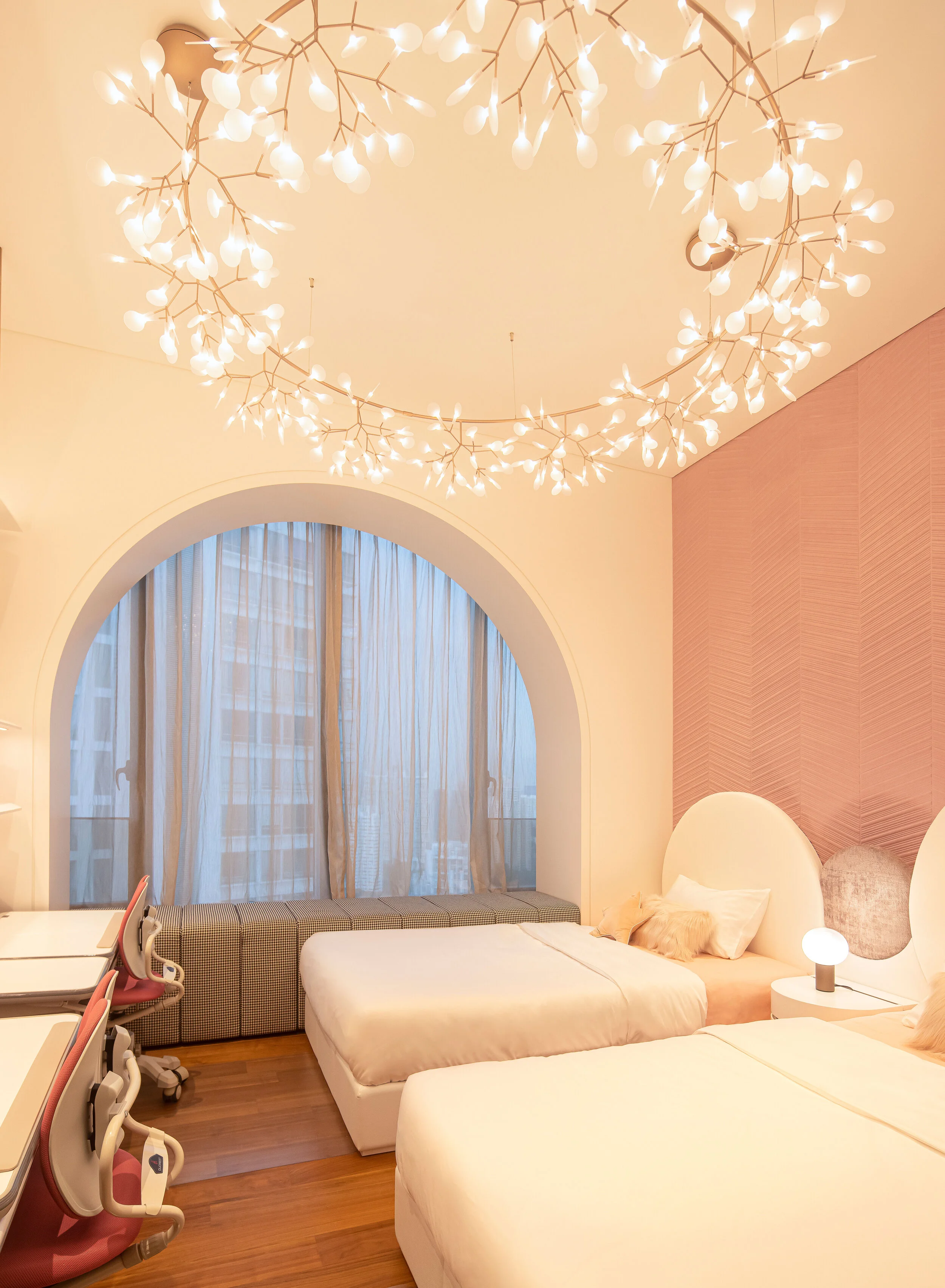 children's bedroom with pink wall, large chandelier and arched windows