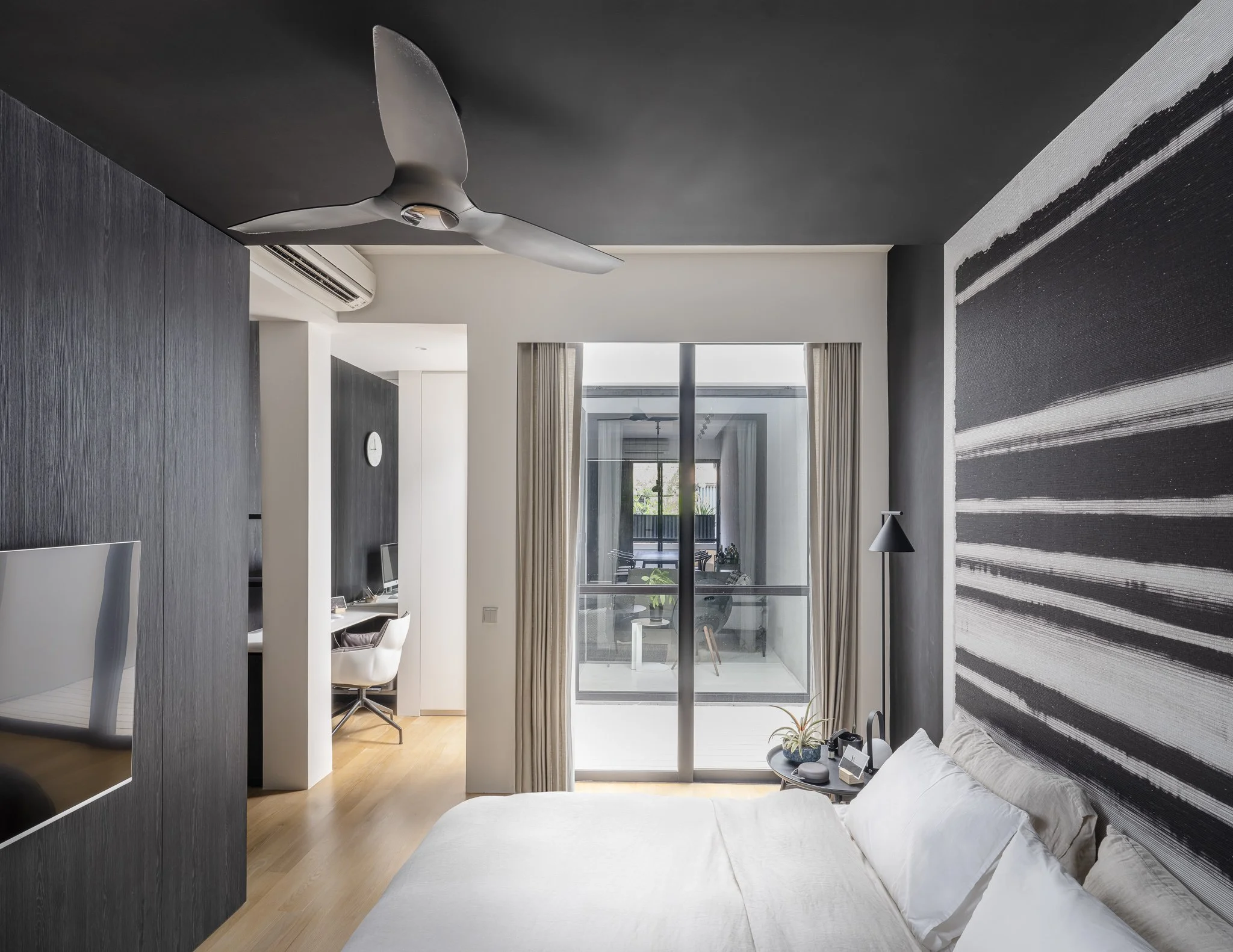 master bedroom in monochromatic black and white scheme, with white bed and full floor to ceiling height windows