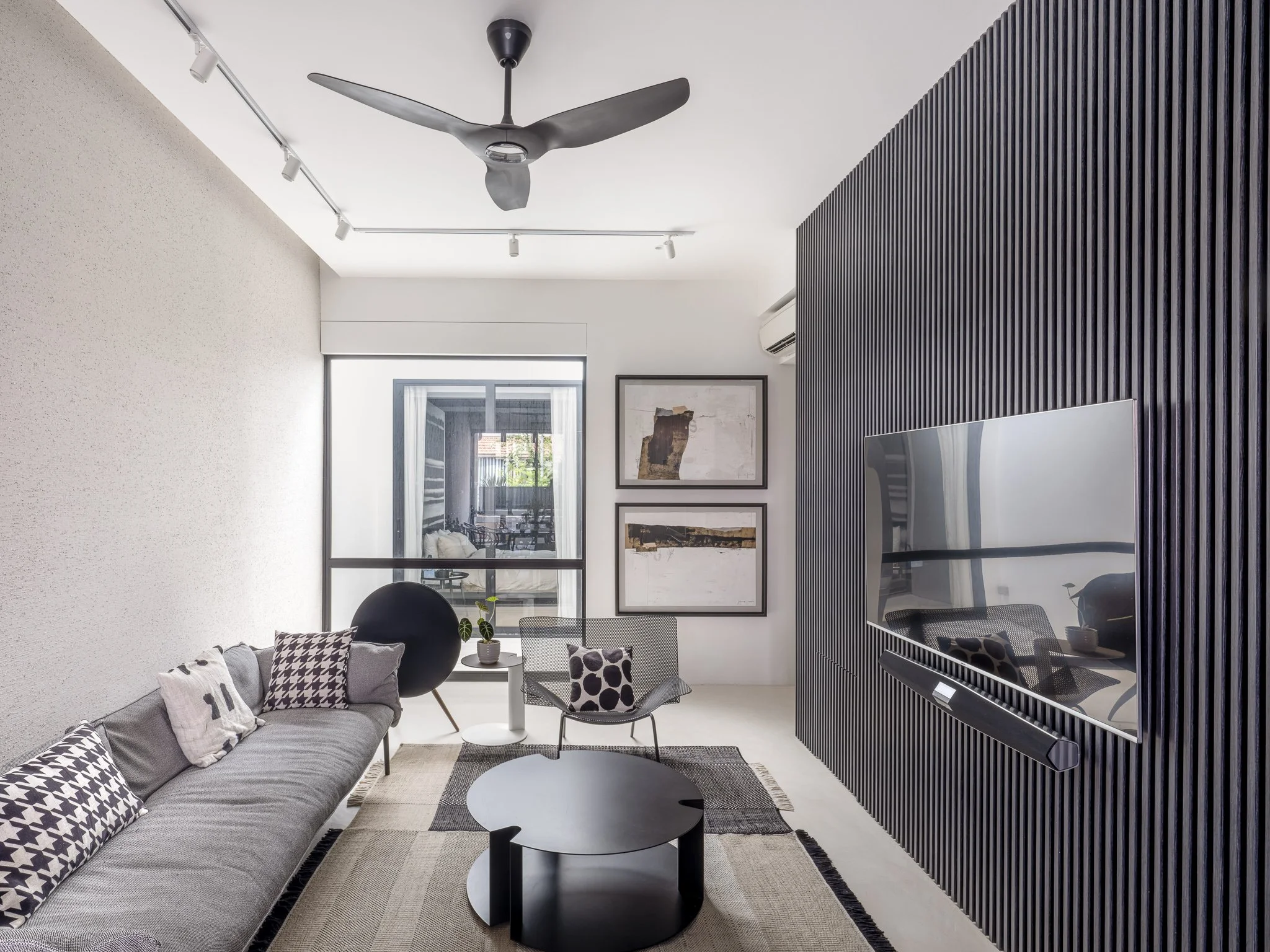 living area with sofa, coffee table, armchair and television mounted on fluted panel wall