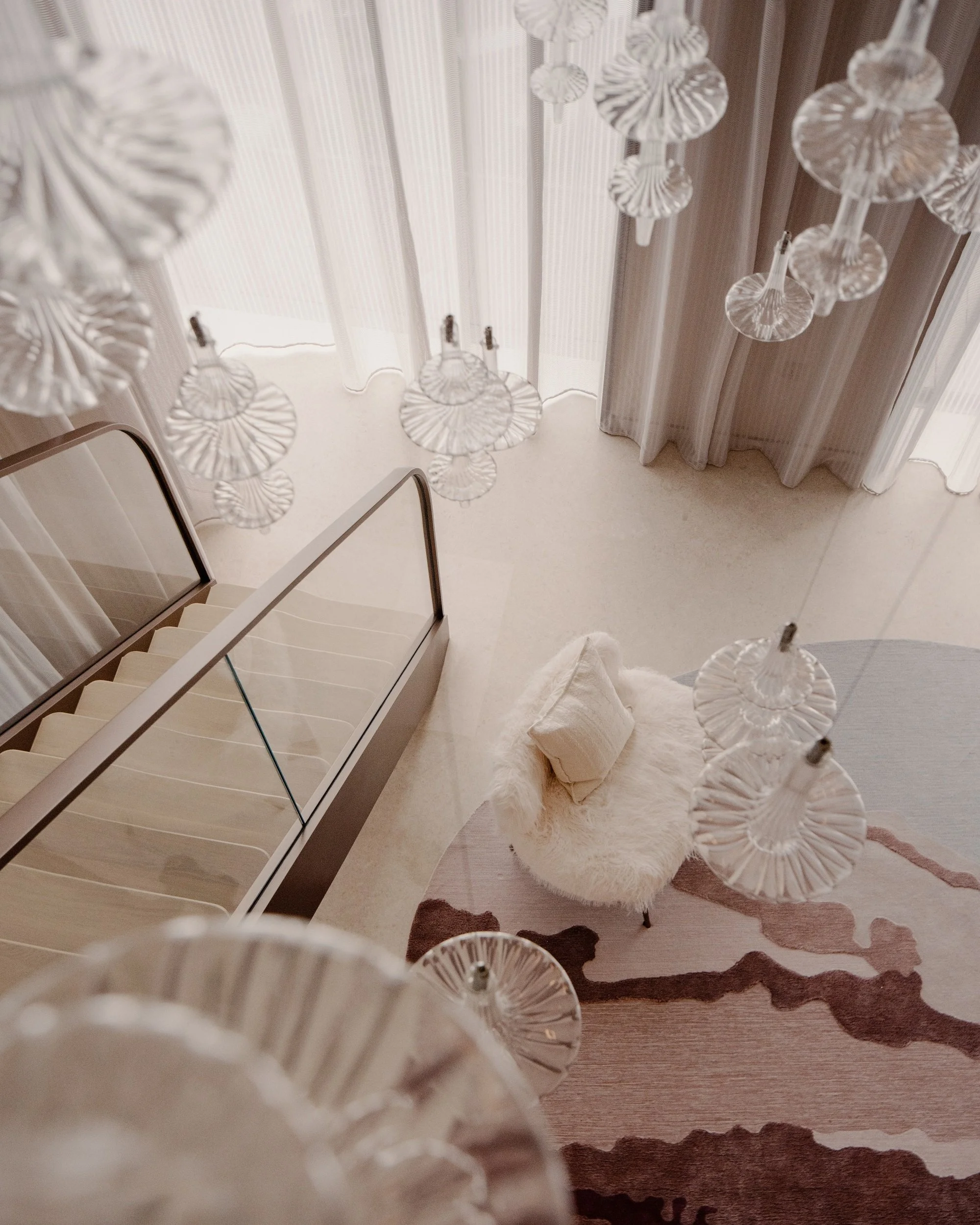 View of the living room carpet and chandelier from the staircase