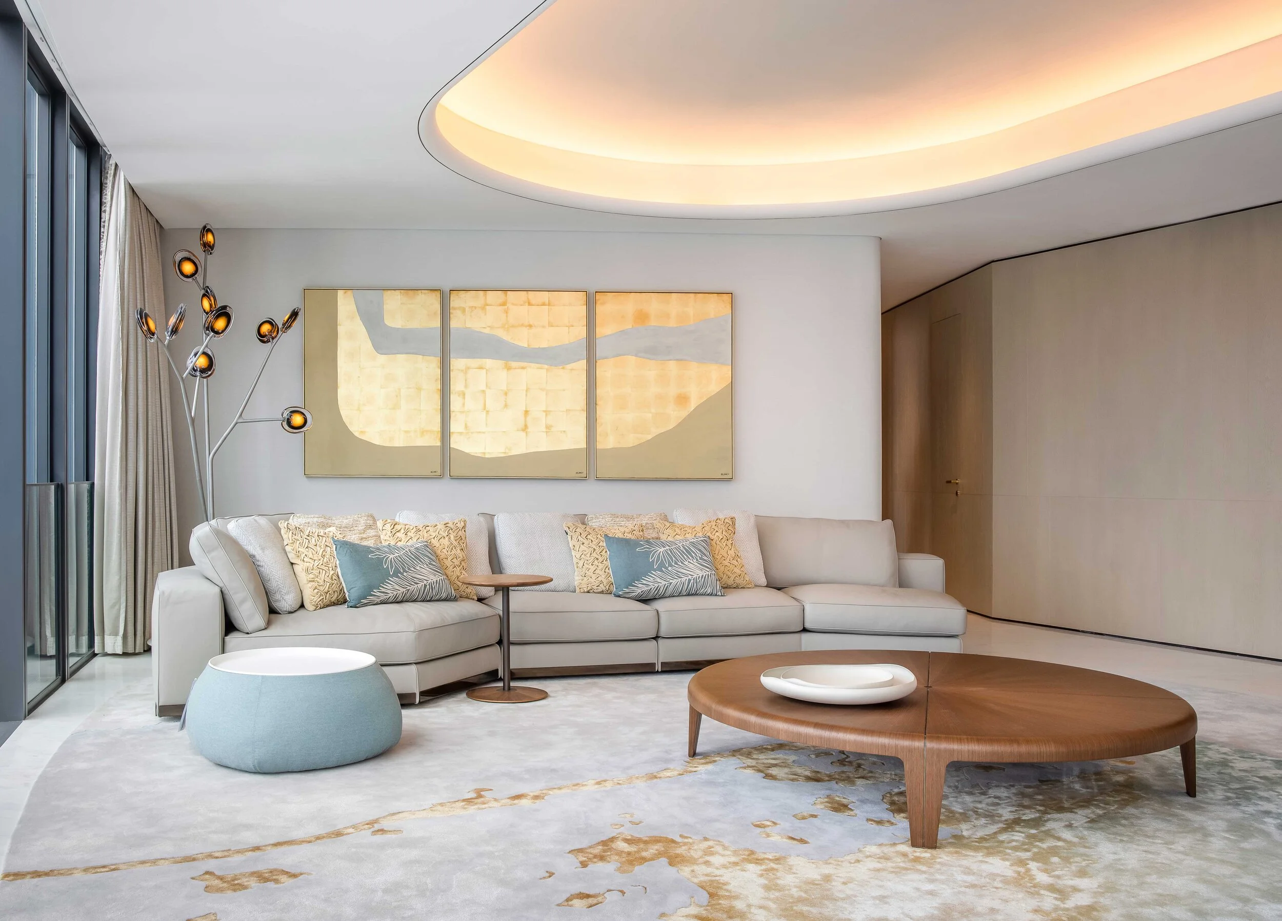 living room with grey sofa, ottoman, large round wood coffee table and artwork on wall