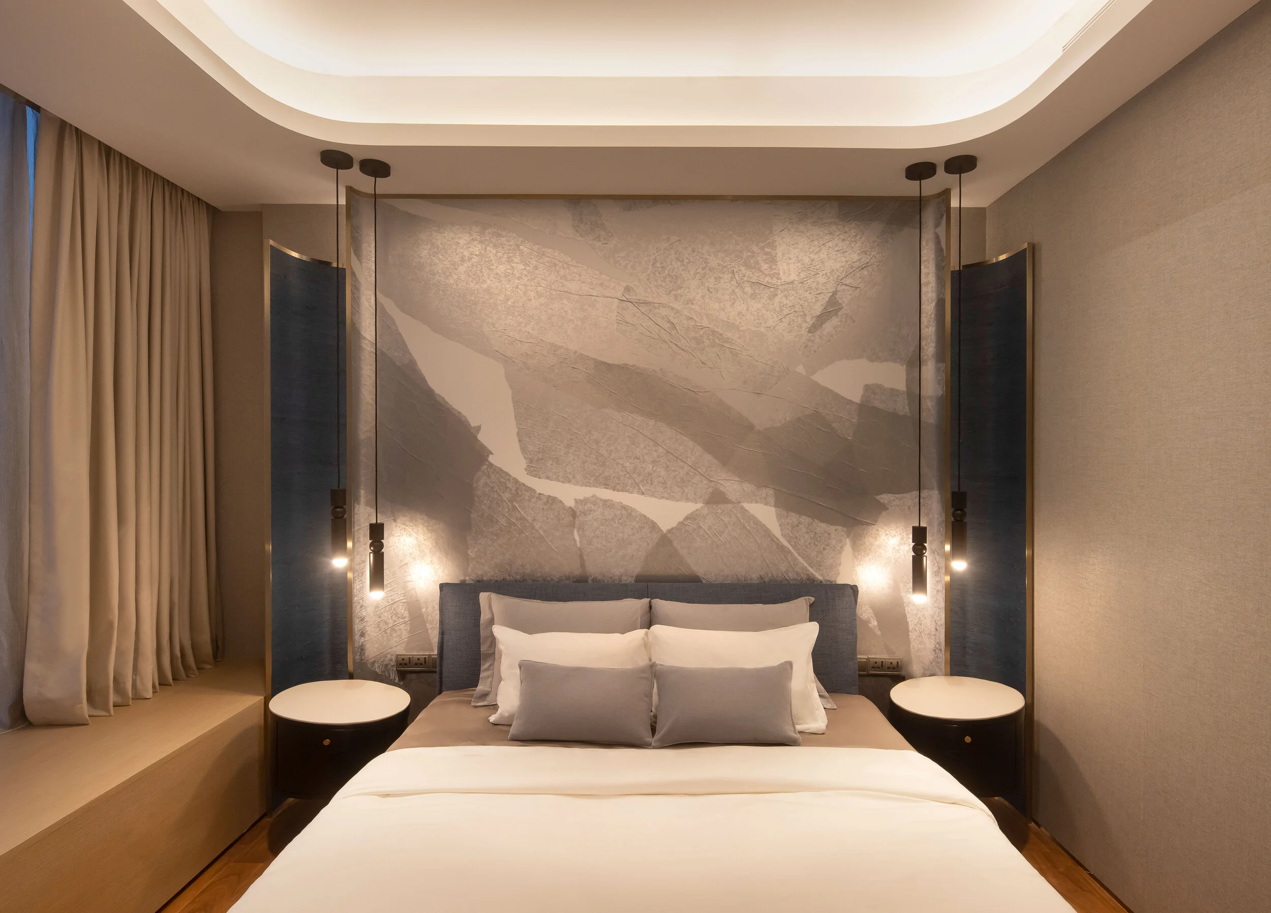 bed with grey patterned headboard  and two round side tables