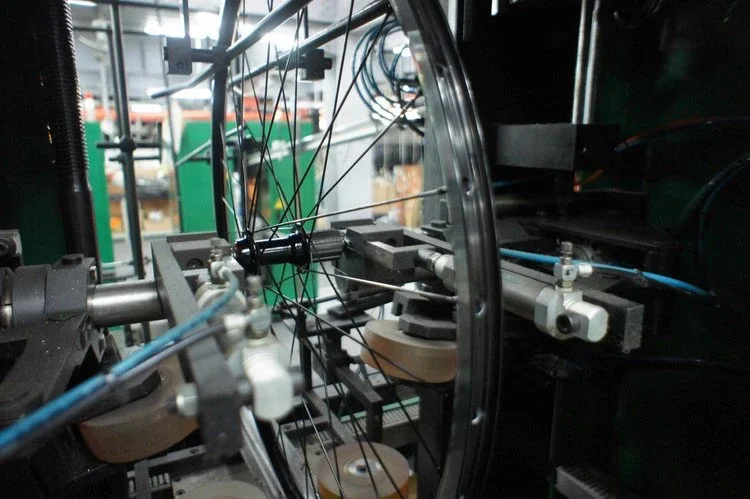 Close-up of a robotic or industrial machine component with metal parts, wires, and rollers, possibly part of a high-tech manufacturing or assembly system.