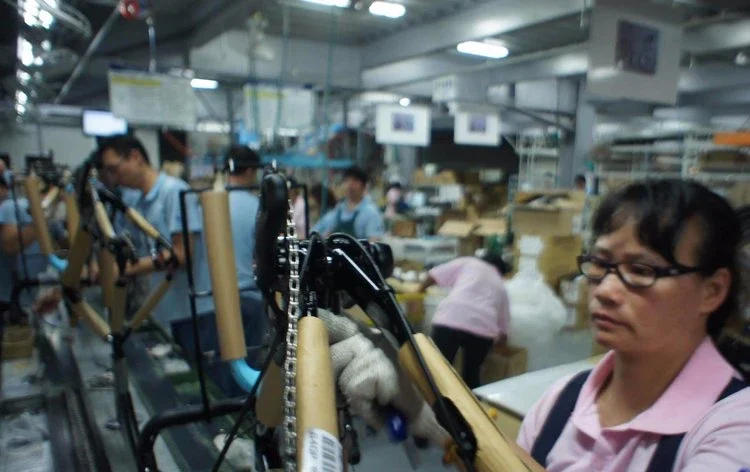 Workers assembling and inspecting bicycles in a factory production line.