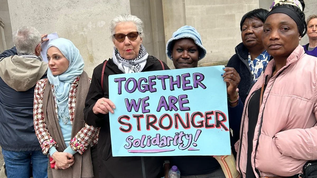 Five women from our network stand outside together, holding up a banner that reads: Together we are stronger. Solidarity!