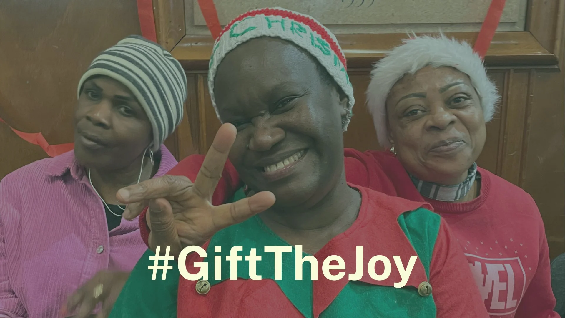 Three of our women members dressed in Christmas outfits  smile at the camera making a peace sign