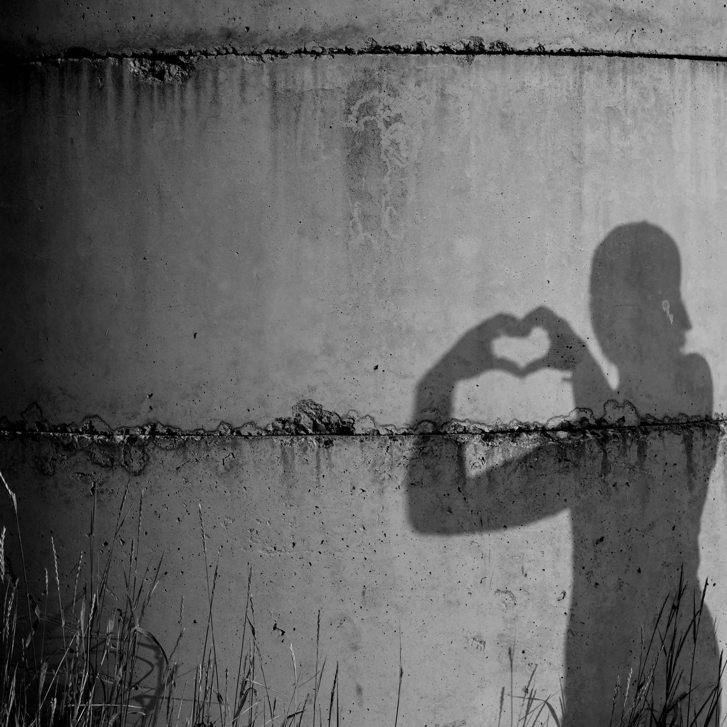 Shadow of a person making a heart shape with their hands, symbolizing gratitude, self-reflection, and emotional resilience.