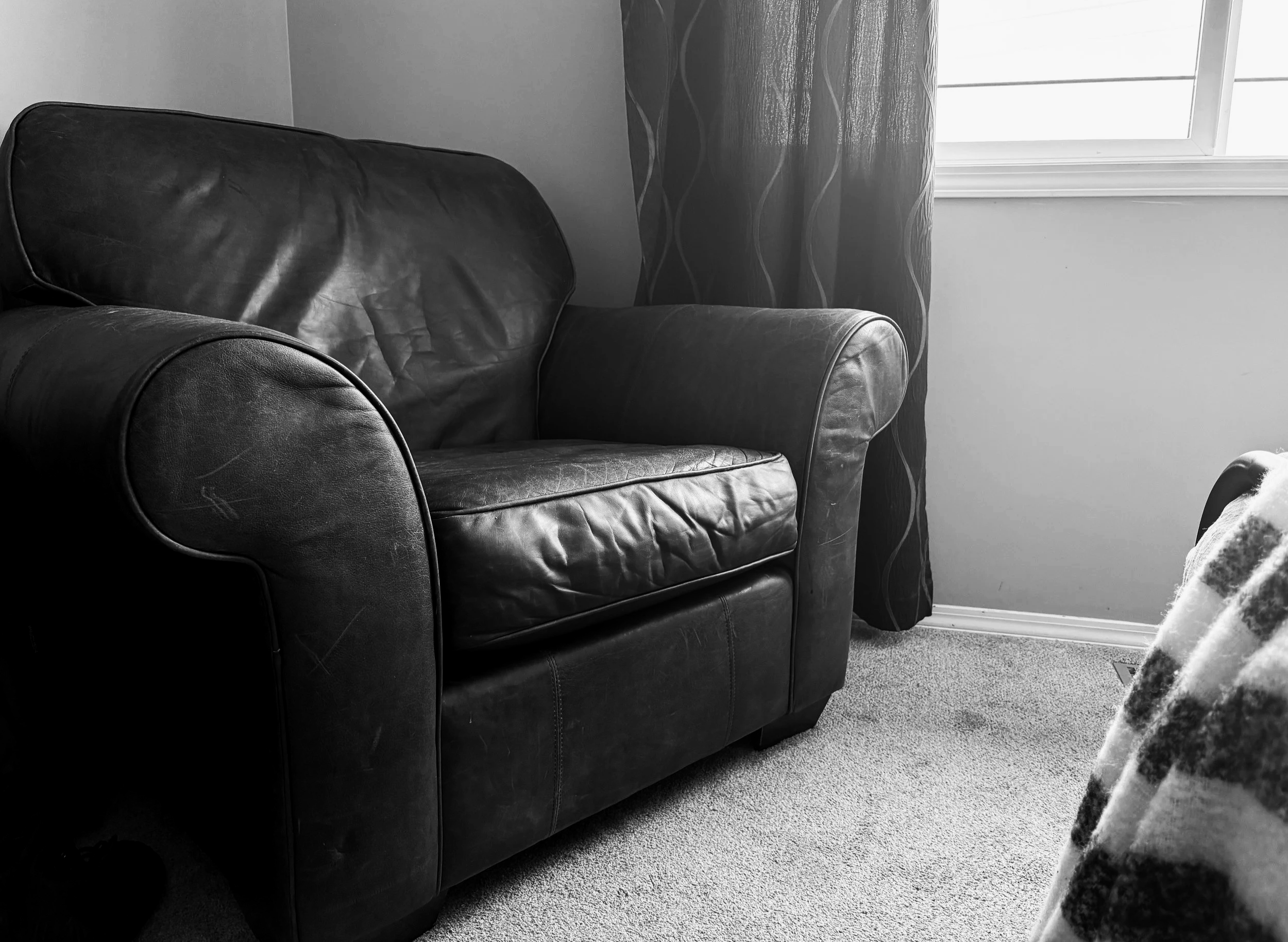 Empty leather armchair beside a bright window in a quiet room.