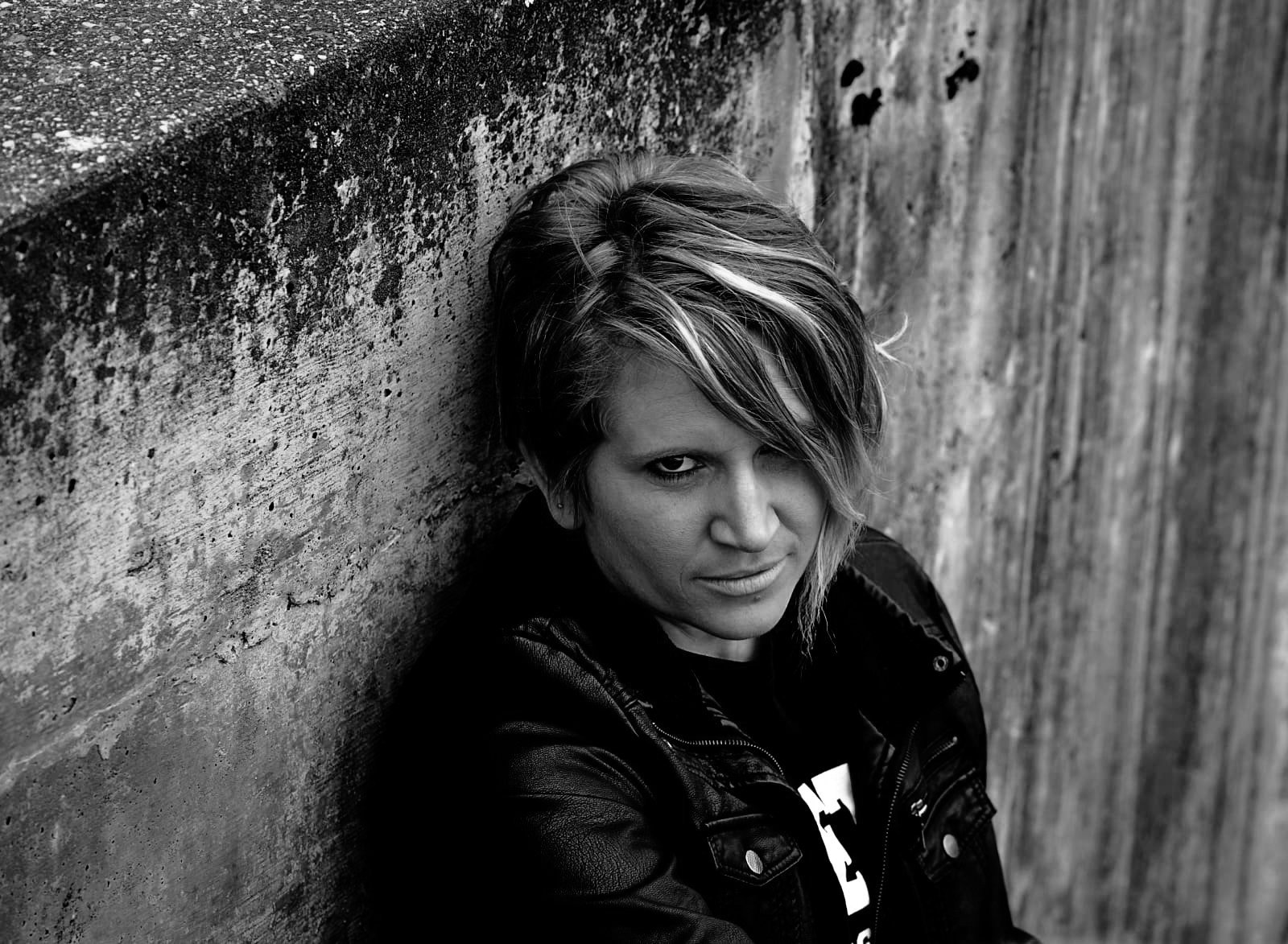 Melissa Lynn Sharp sitting on a concrete staircase looking confidently toward the camera, representing resilience, acceptance, and inner strength.