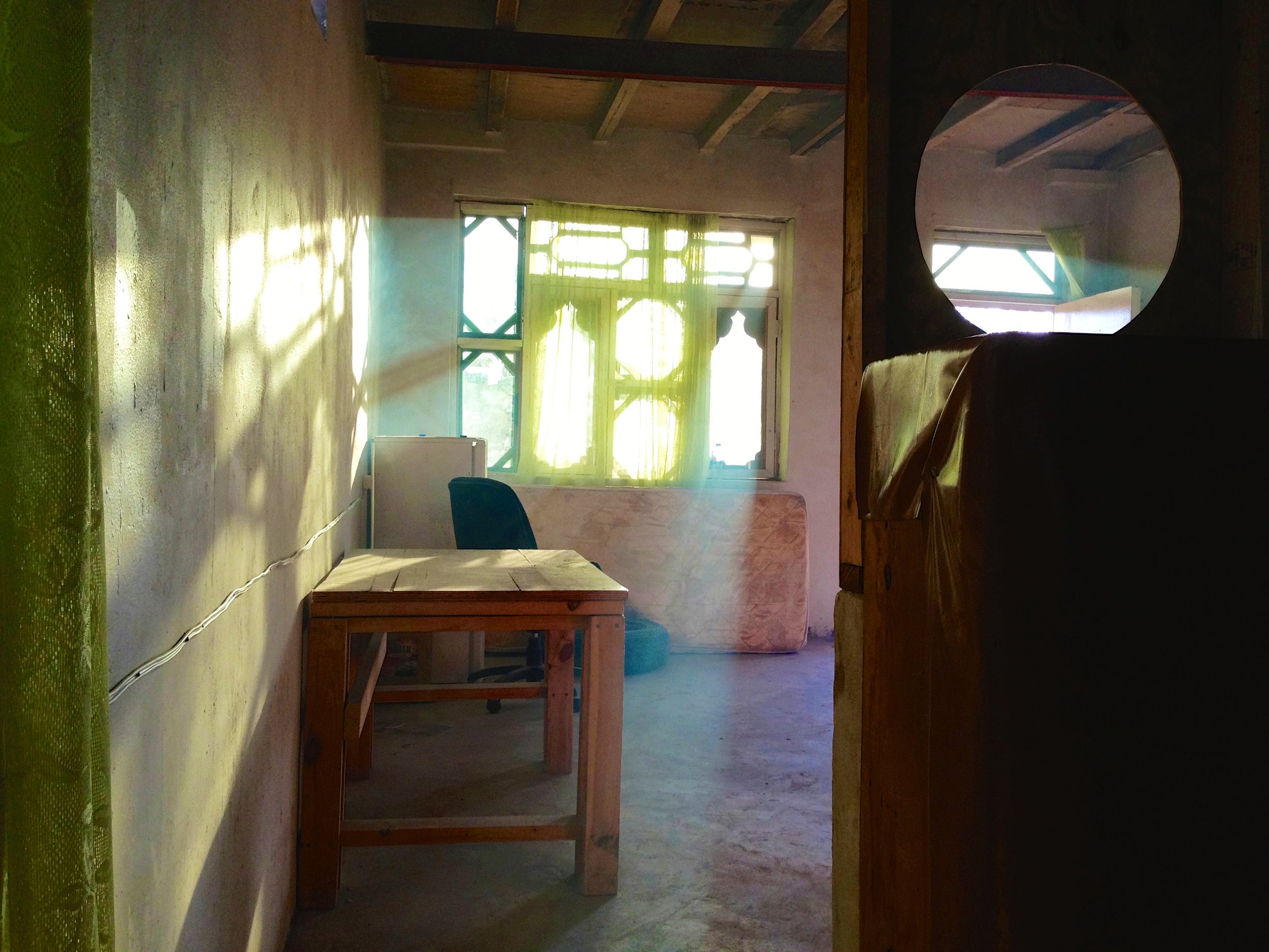 An empty chair beside a window in a bakery in Jalalabad, Afghanistan, illuminated by soft morning light, representing the coexistence of hardship, hope, and moments of peace.