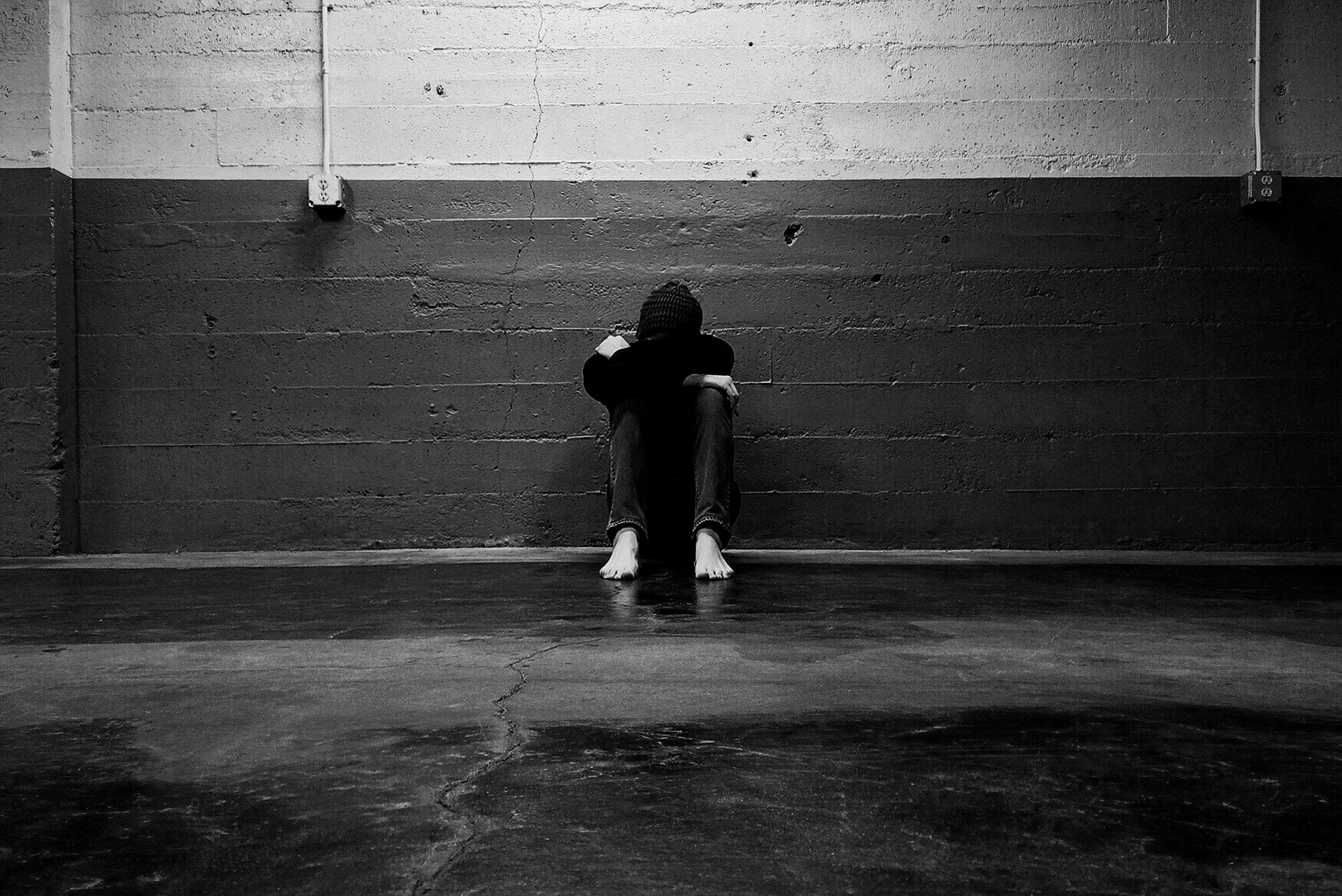 Person sitting alone against a wall, symbolizing self-forgiveness, emotional healing, and letting go of resentment.