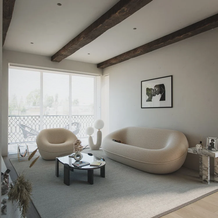 Curved seating beneath exposed timber beams, with soft daylight through a window.