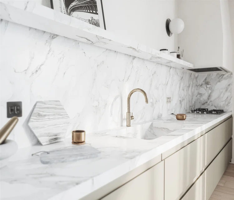 A marble kitchen and brass tap, shown in close detail.