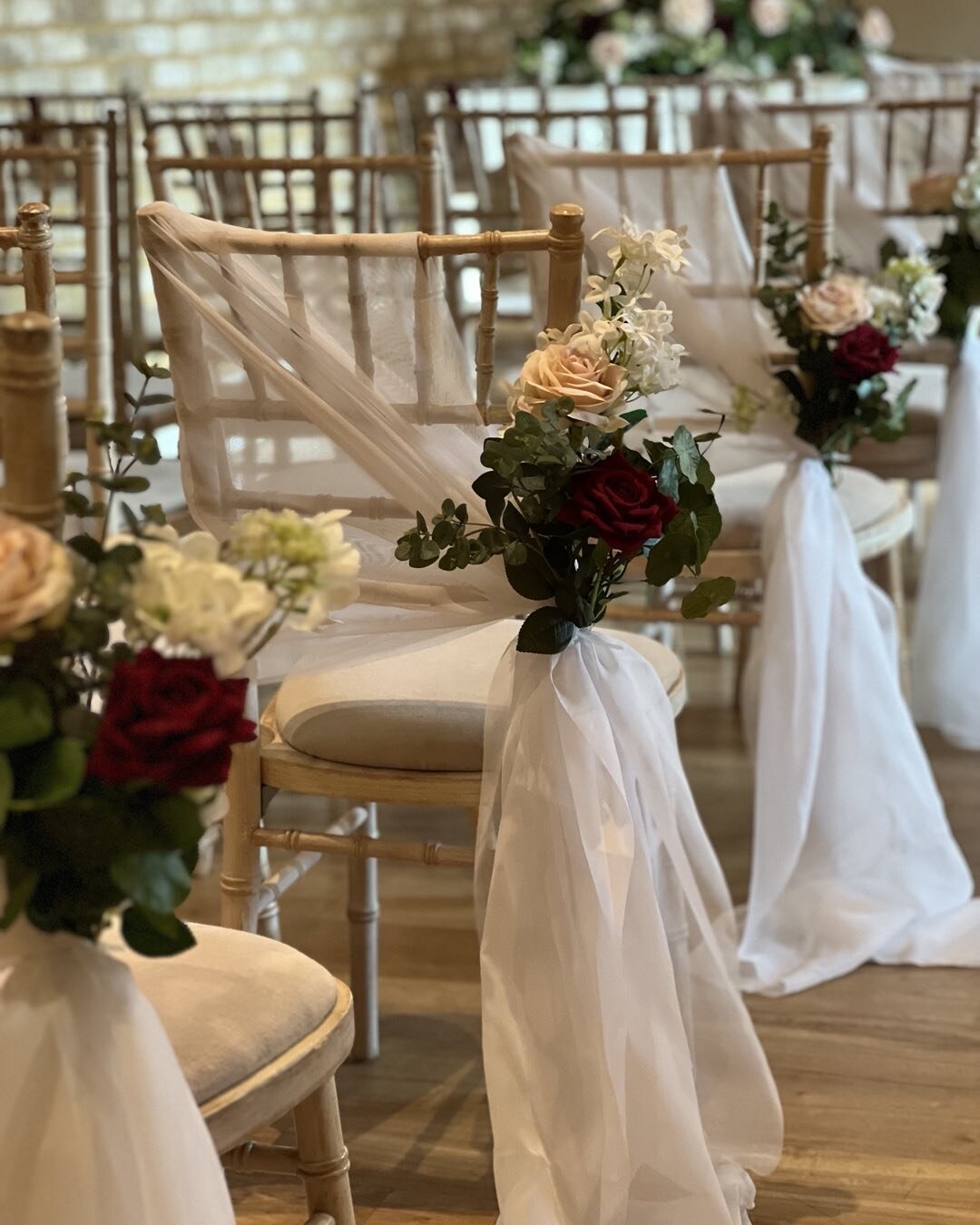 Aisle decoration. A small posy of flowers tied with organza to each inner chair. Framing the aisle perfectly.
#fauxflowerwedding #fauxweddingflowers #surreyweddings #guildfordflorist