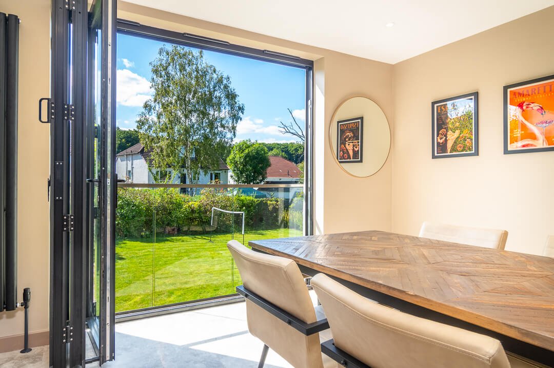 Bifold doors open to sunny garden from dining area in Bearsden home by Interior Space Design Glasgow