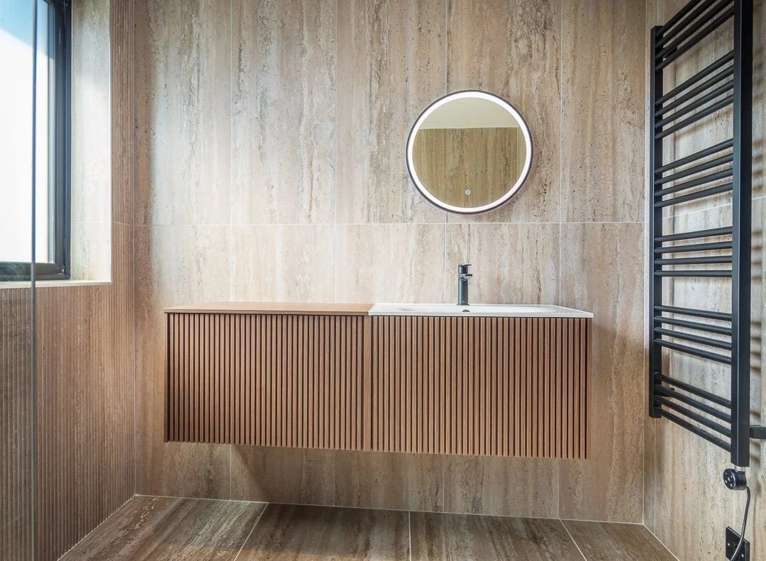 Boutique hotel style master bathroom with ribbed oak wall hung vanity unit LED demister mirror and travertine tiles in Bearsden by Interior Space Design Glasgow