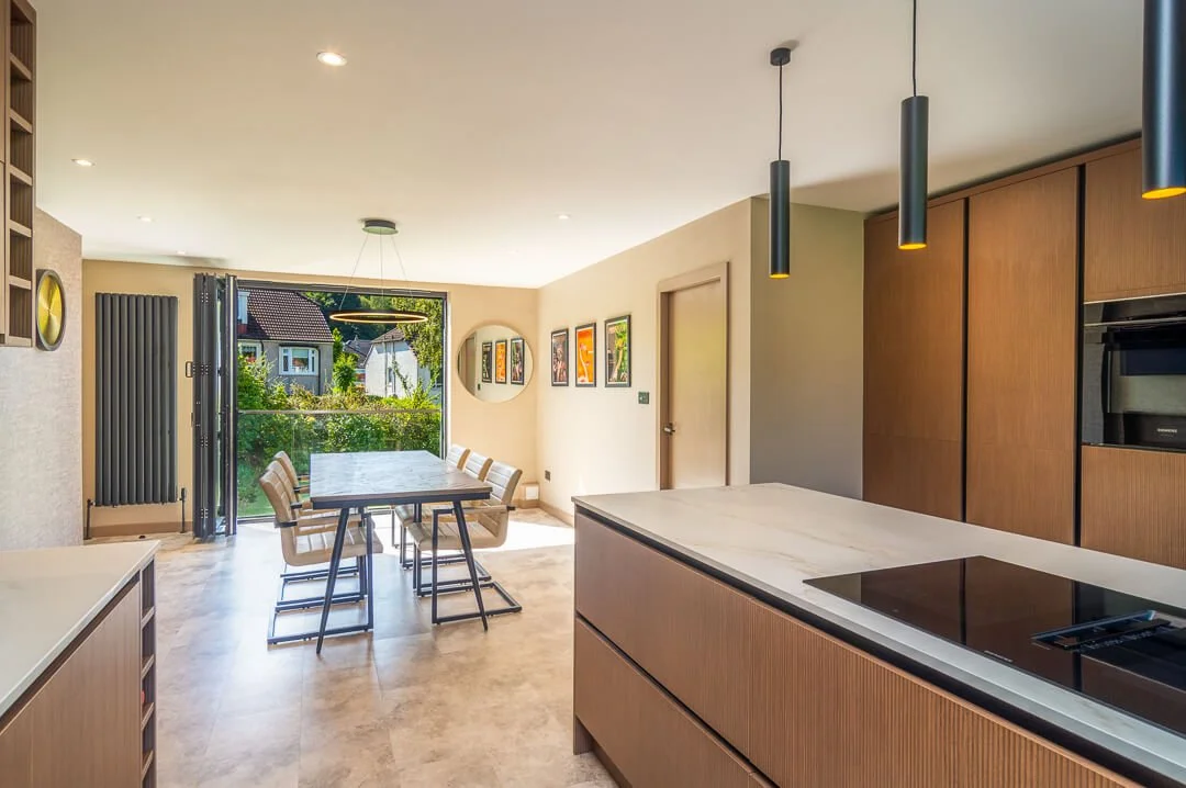 Kitchen island with ribbed oak units flowing through to open plan dining area and garden in Bearsden by Interior Space Design Glasgow