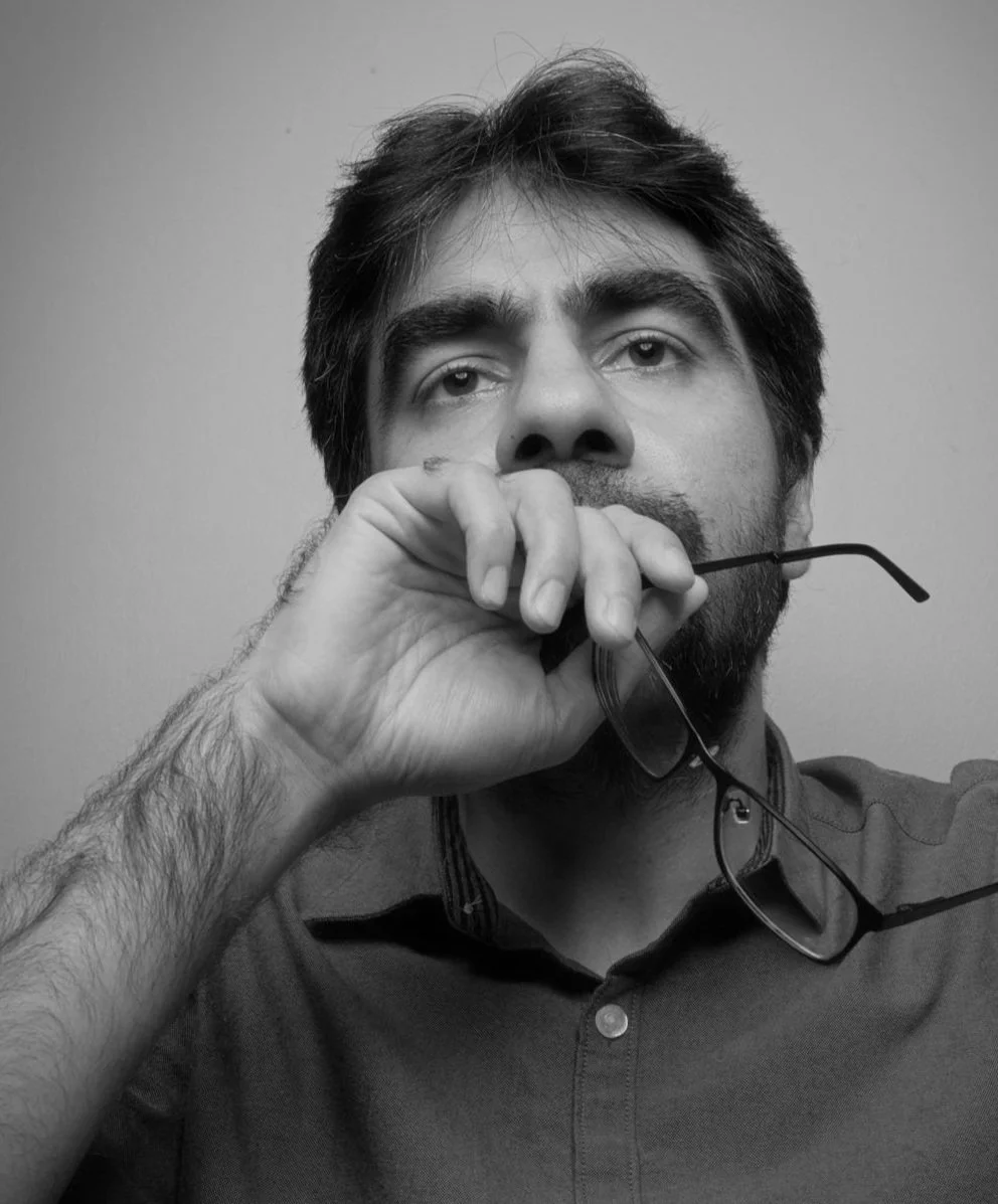 Black and white self-portrait of commercial photographer and image editor Hammad Iqbal holding glasses in Doha Qatar