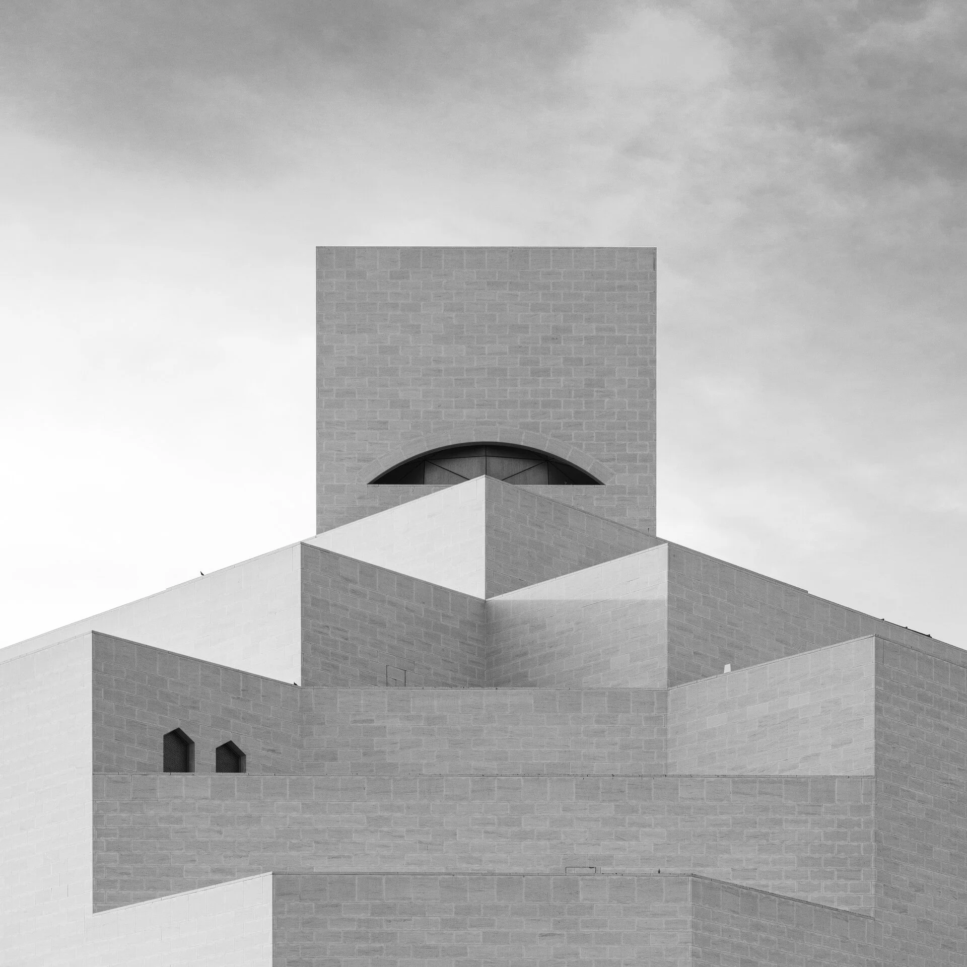 Square black and white symmetrical shot of I.M. Pei's Museum of Islamic Art exterior highlighting geometric limestone blocks and top window by Hammad Iqbal