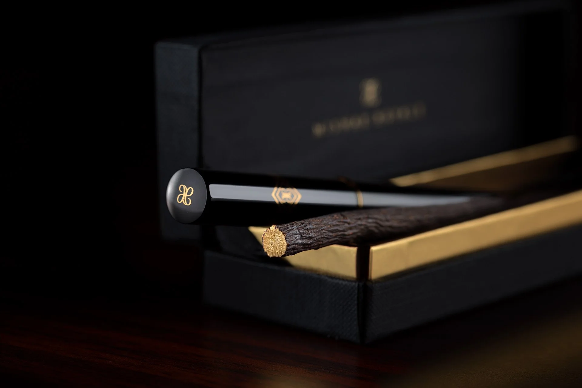 Macro shot of natural Kashmiri olive wood miswak stick resting inside custom black and gold casing by Hammad Iqbal