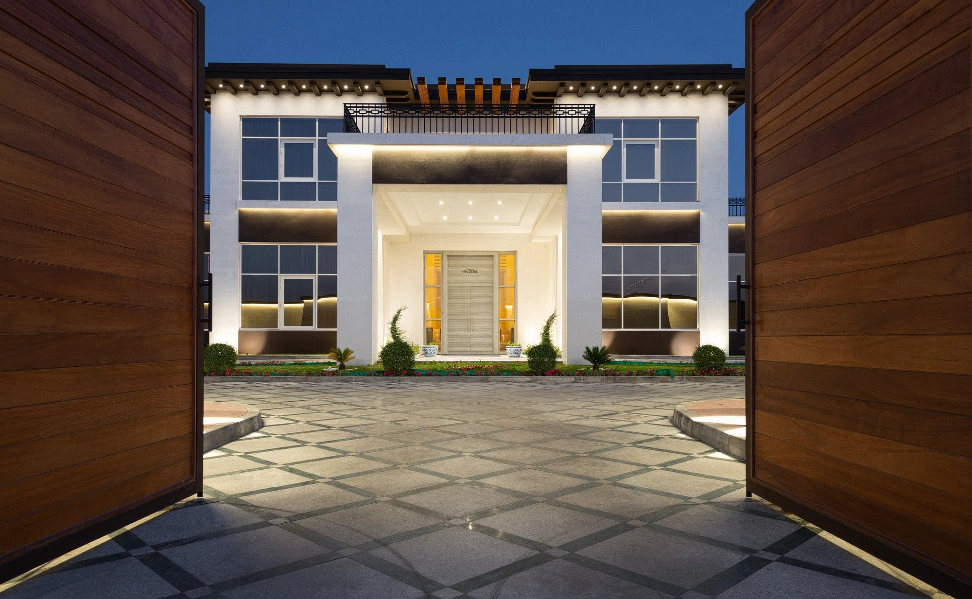 Symmetrical twilight exterior photo of luxury villa entry gates and illuminated entrance facade in West Wukair Qatar by Hammad Iqbal