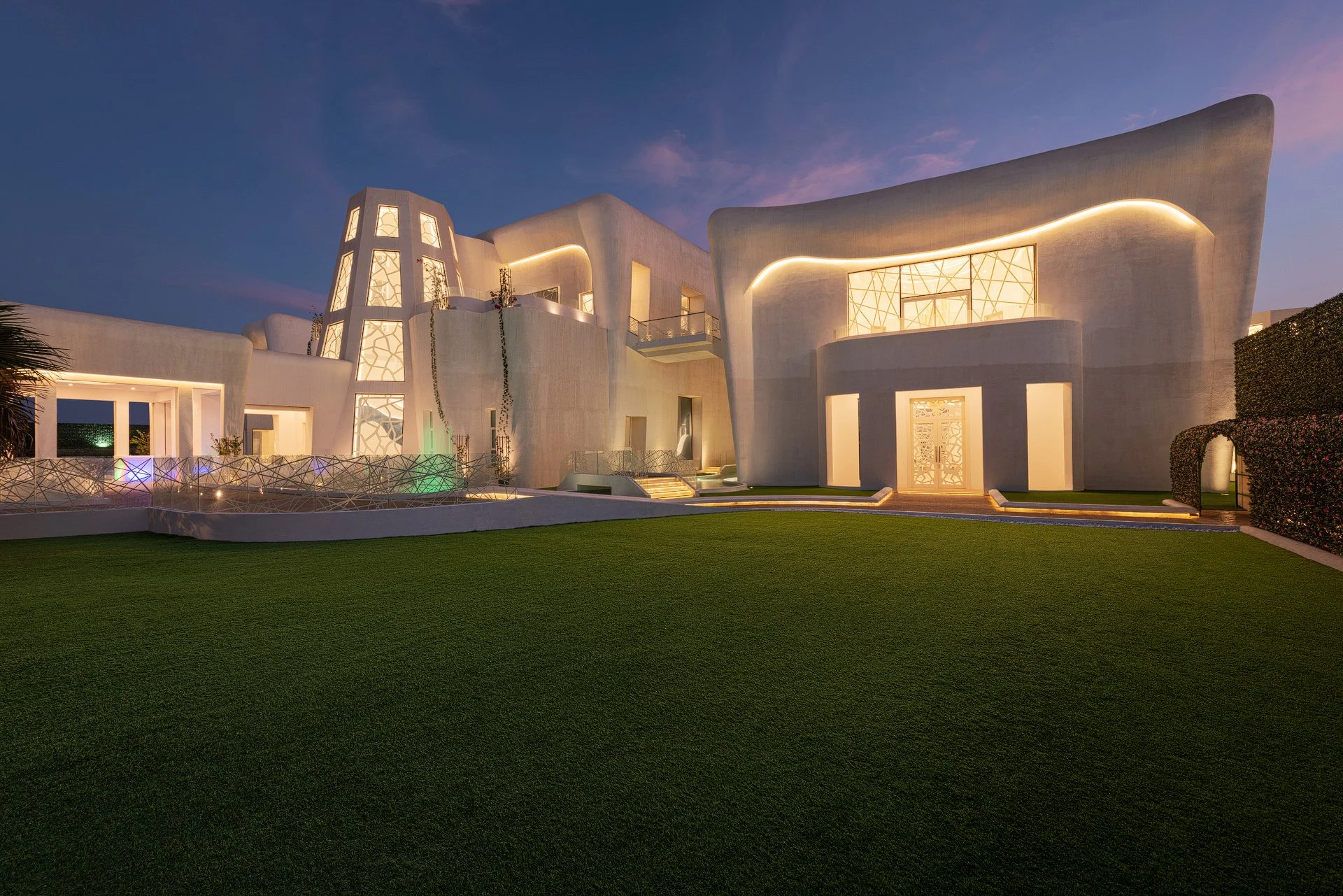 Exterior angle highlighting curved white stucco architecture and integrated LED strip lighting on grass lawn photographed by Hammad Iqbal