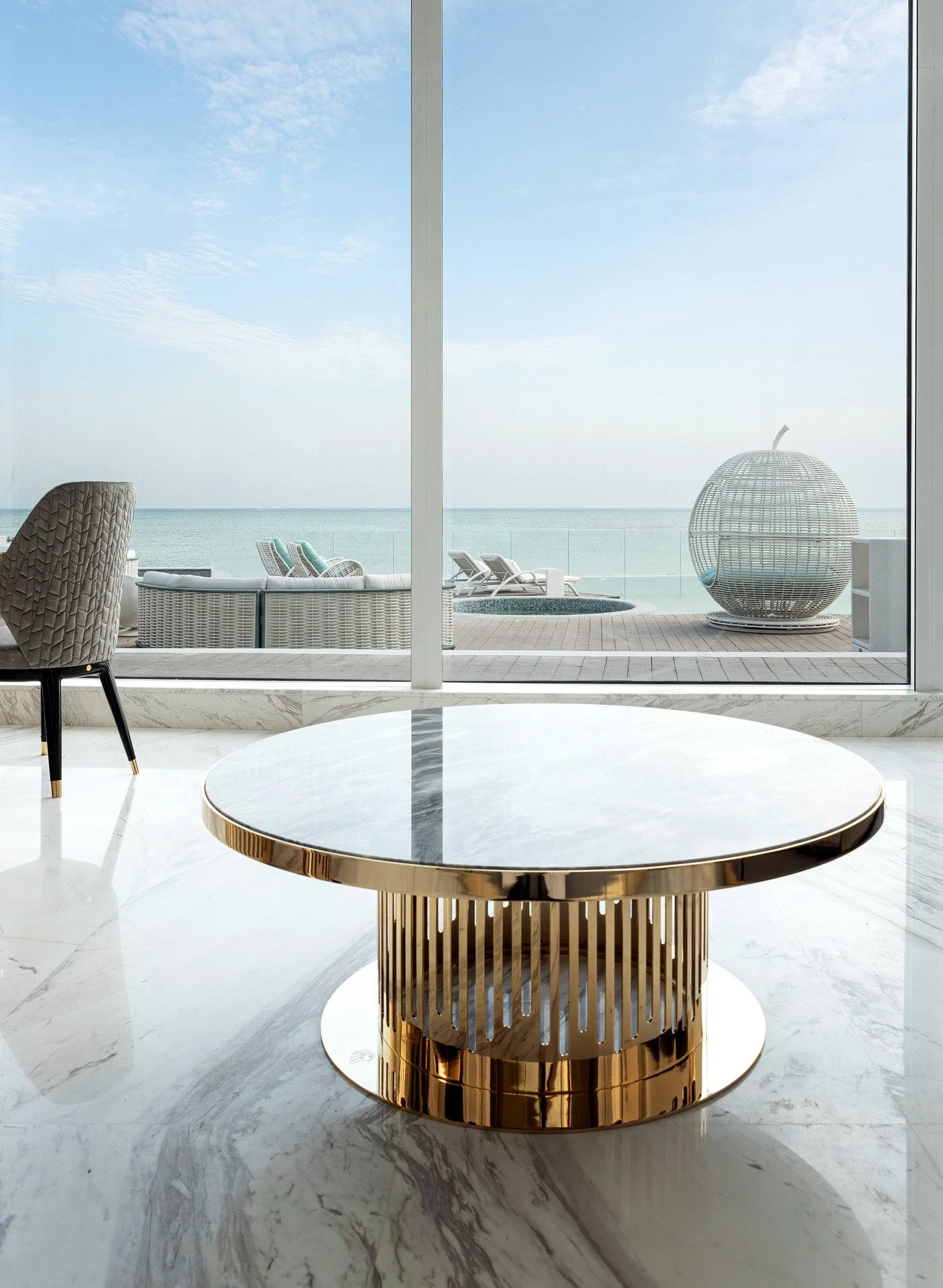 Marble coffee table with brass base framing floor to ceiling sea views at The Coastal Pearl Estate by Hammad Iqbal