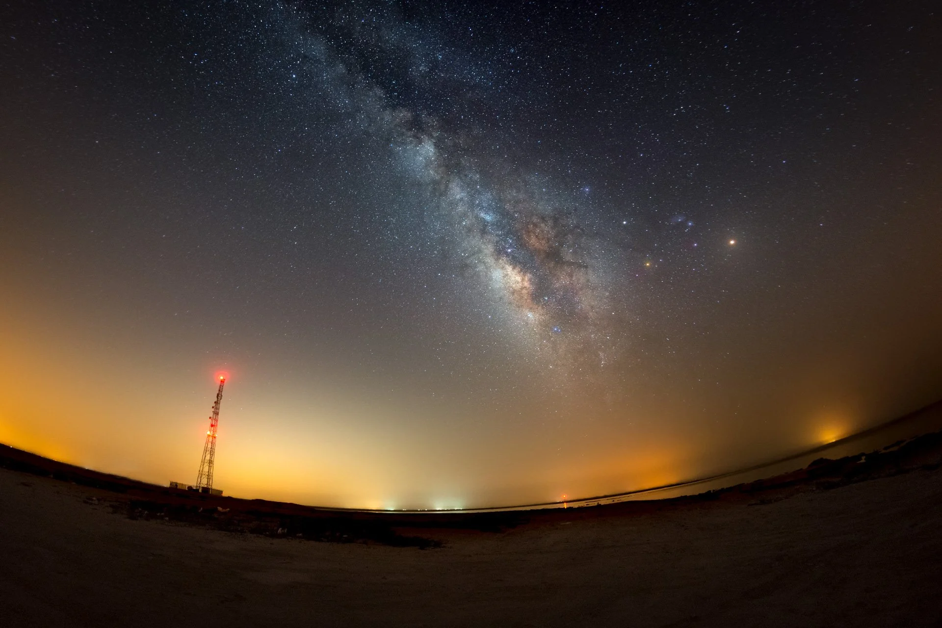 Night photograph of a communication tower silhouette against the Milky Way and horizon glow in Qatar by Hammad Iqbal