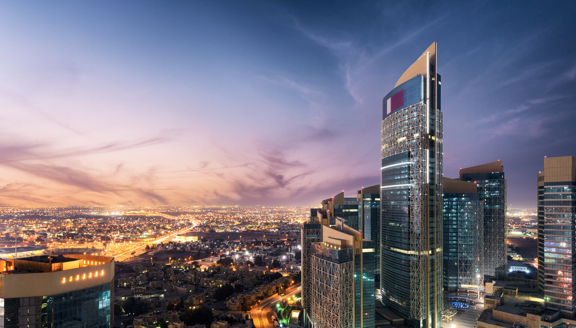Elevated rooftop view overlooking West Bay skyscrapers bathed in warm sunset light in Doha by Hammad Iqbal
